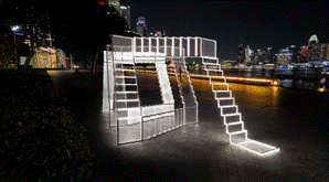 Illuminated scaffolding staircase structure by the waterfront at night