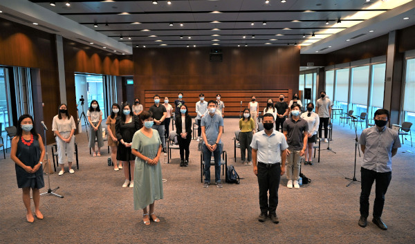 Group photo of 30+ masked people standing distanced in a room.