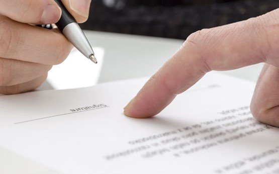 Close-up of a hand holding a pen, signing a document
