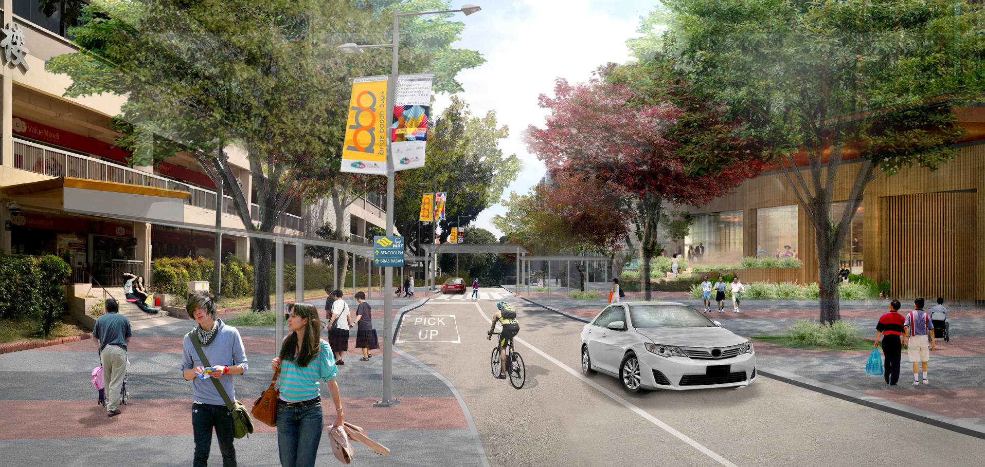 A street scene with people walking and cycling, a car, trees, and buildings on either side of the street. Banners hang from lampposts.