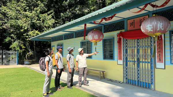 A tour guide showing a group a traditional Chinese building with red lanterns and calligraphy.