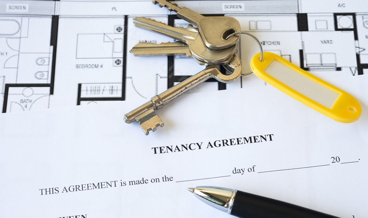 Keys on tenancy agreement document with floor plan and pen, representing property rental.