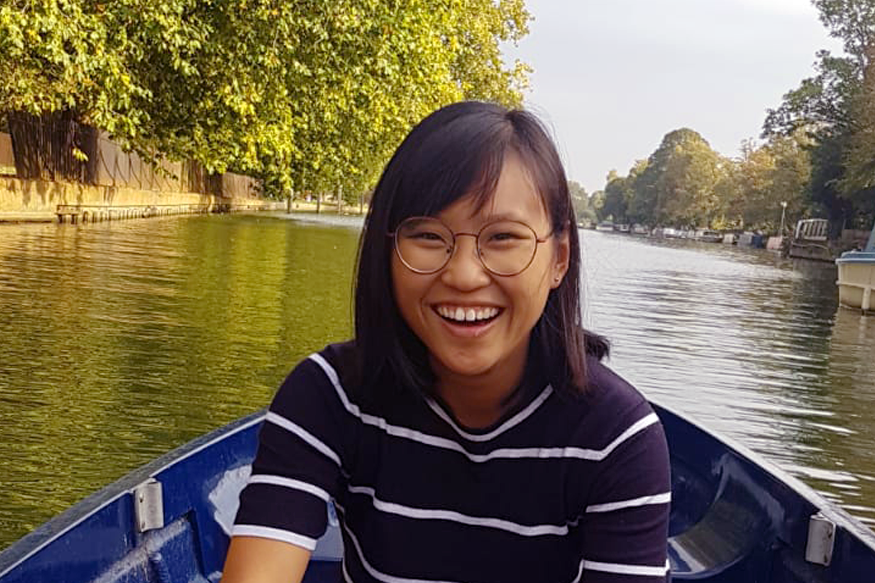 Wu Jia Min, URA Scholar, smiling while rowing a boat on a river