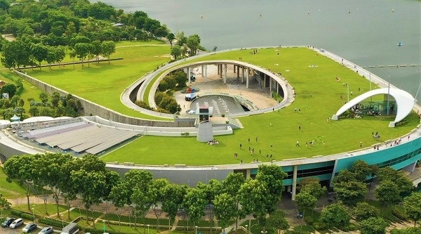 Aerial view of a building with a large green roof and a circular opening. People are on the roof.