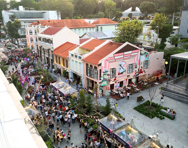 A high-angle shot of a bustling street fair with colorful buildings and many people.