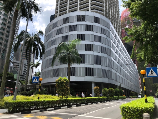 View of International Plaza with palm trees and a busy road in front, showcasing the modern architecture.