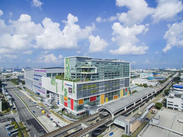View of a large, modern shopping mall, "Causeway Point Mall" in Singapore, adjacent to a train station and highway.