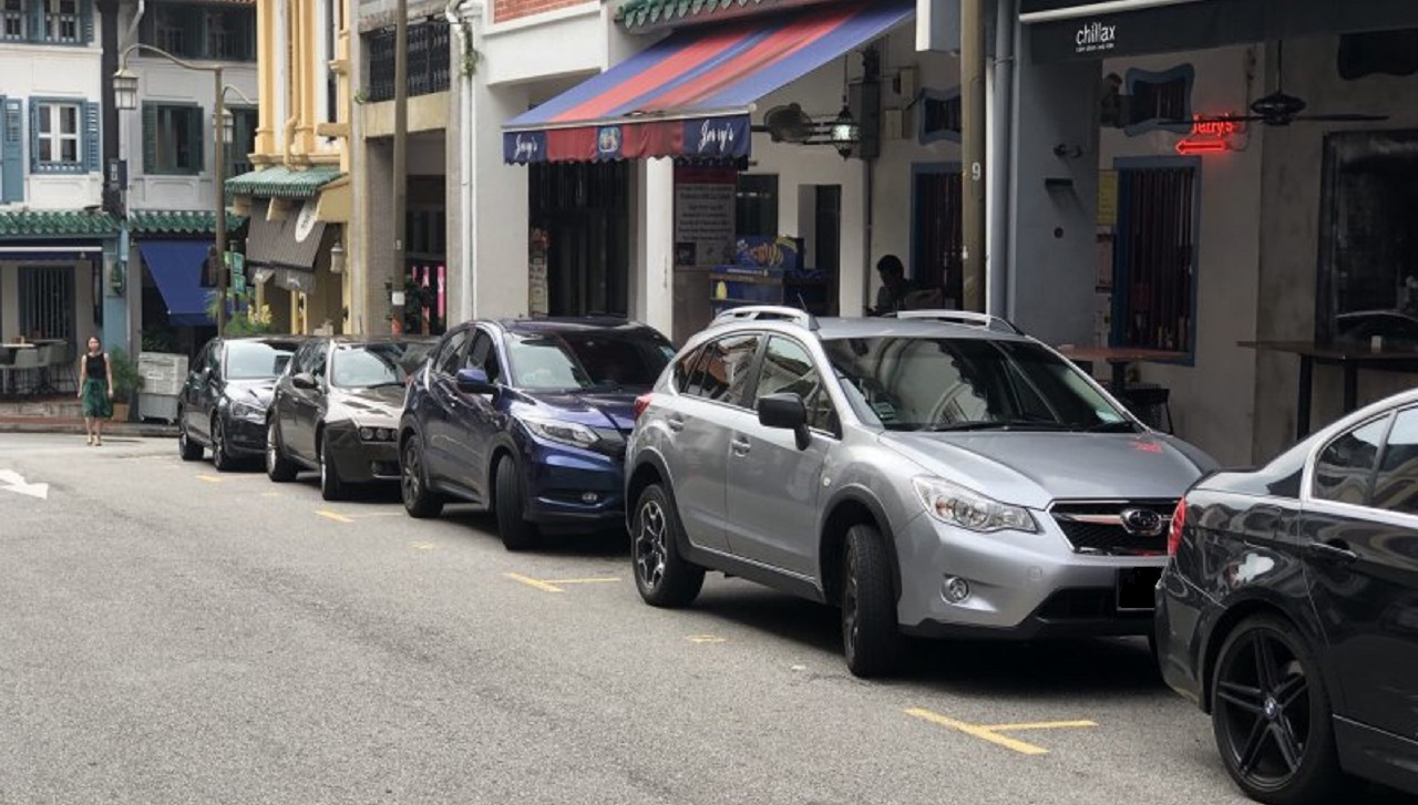 Row of cars parked along street of shophouses