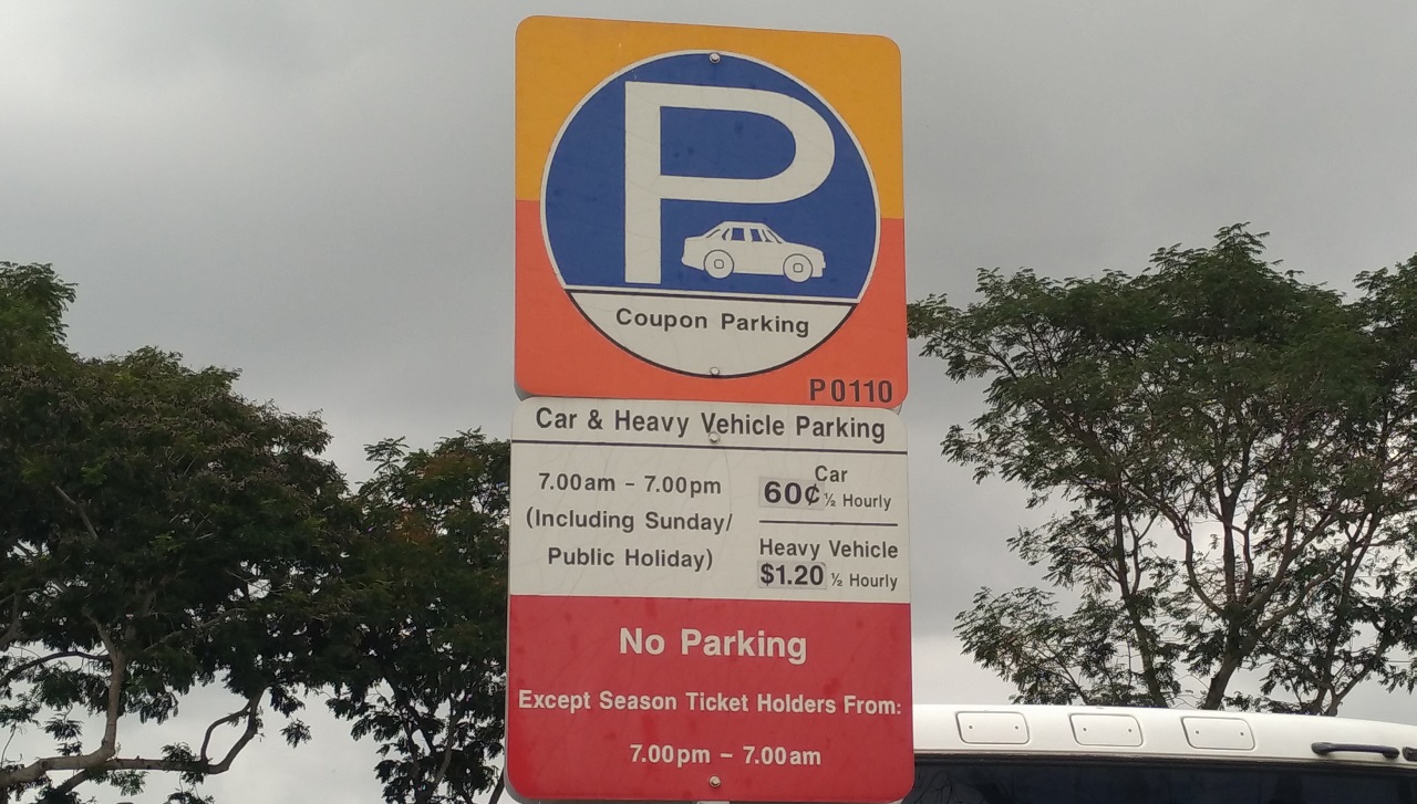 Street sign indicating coupon parking for cars and heavy vehicles with specified rates and hours.