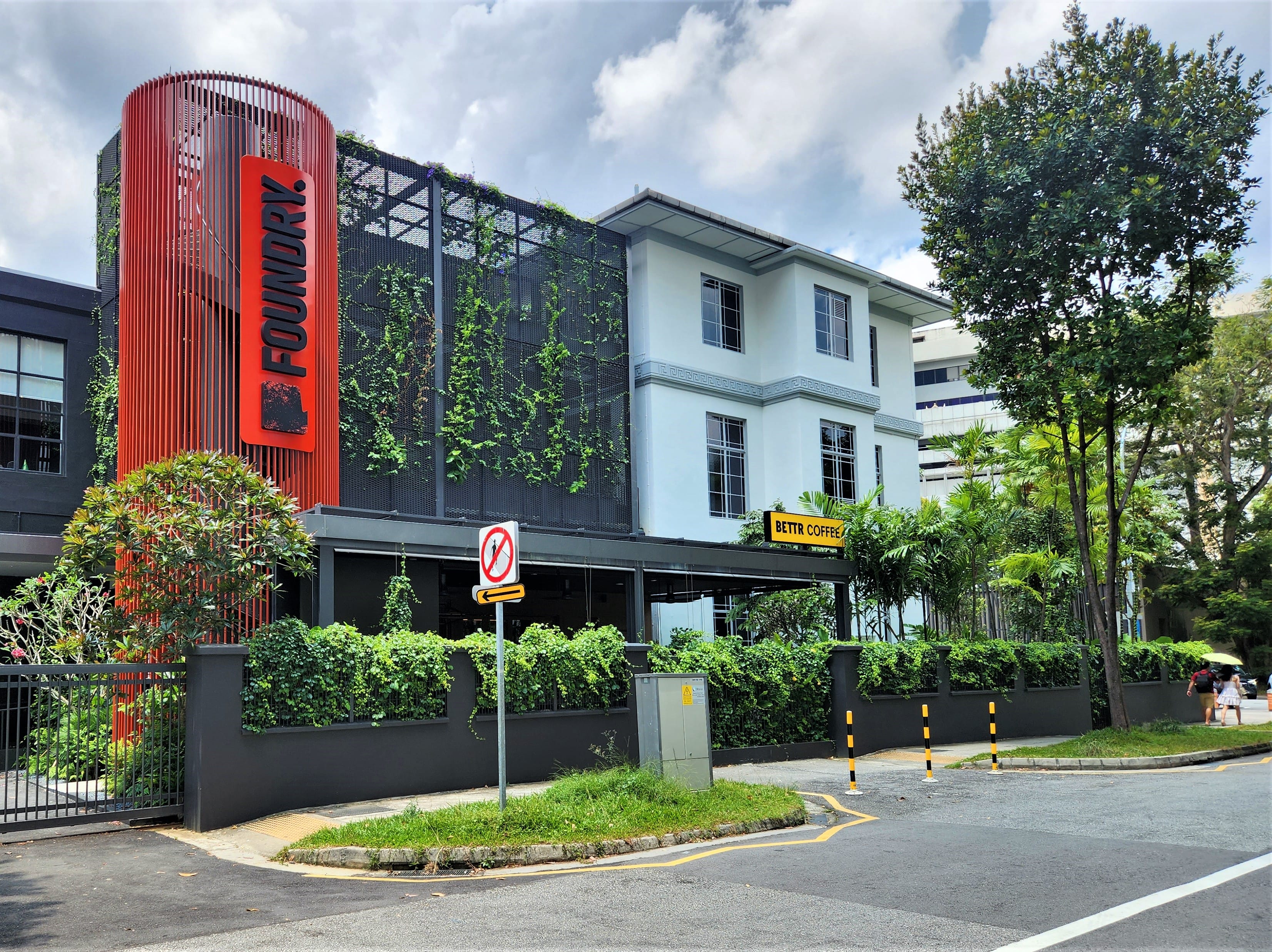 Exterior of "The Foundry" and "Bettr Coffee" building with greenery and modern design elements on a cloudy day.