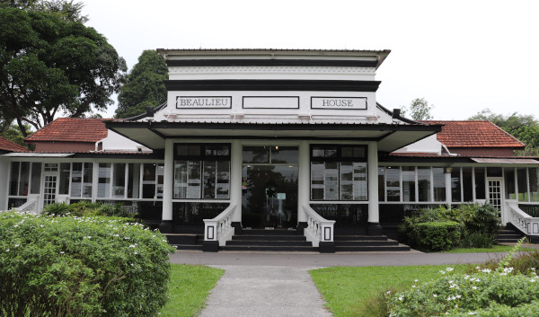 "Beaulieu House" building with white facade and dark trim, surrounded by greenery.