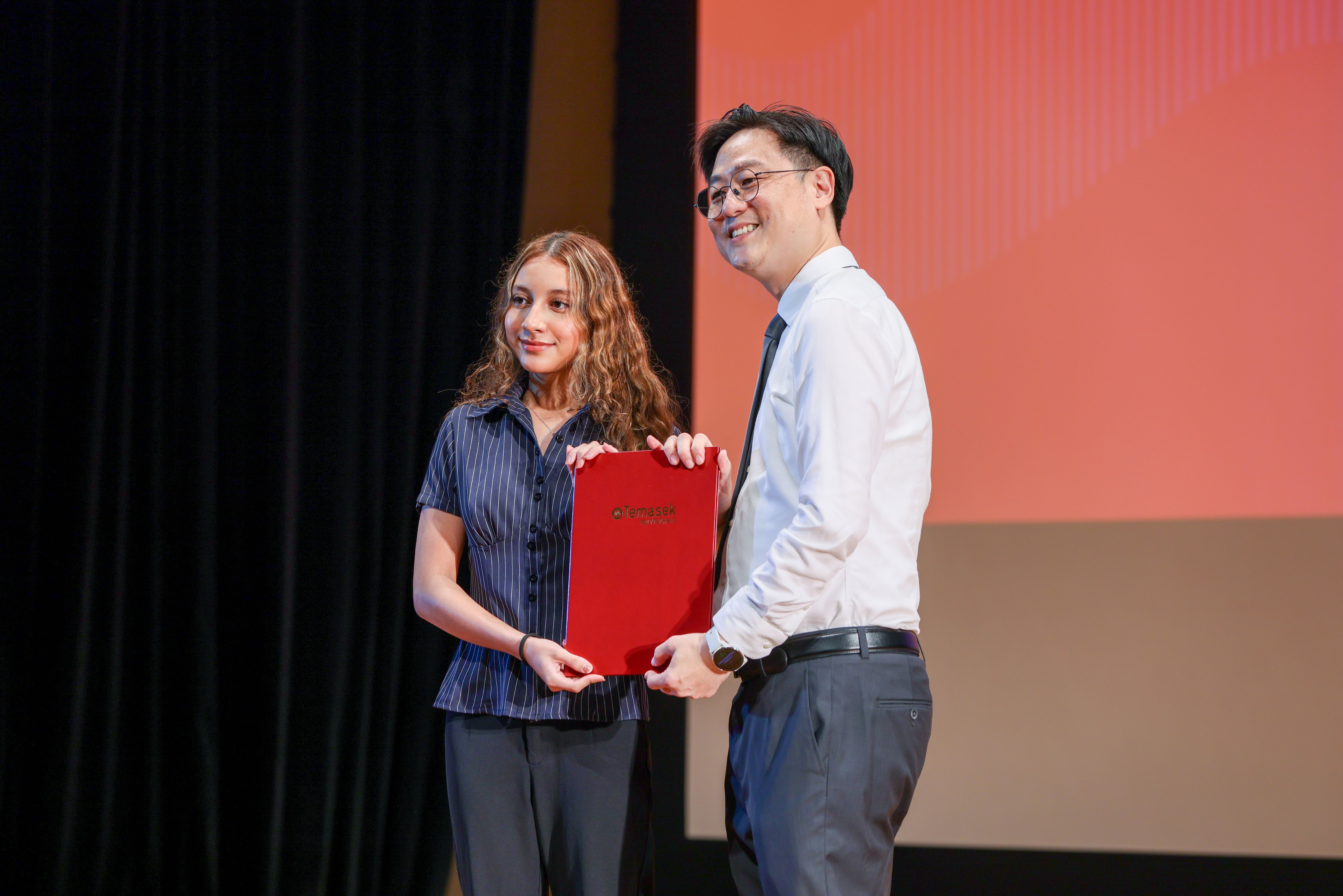 Image of a student posing with Mr Patrice Choong on stage with her certificate at the TP Scholarships Presentation