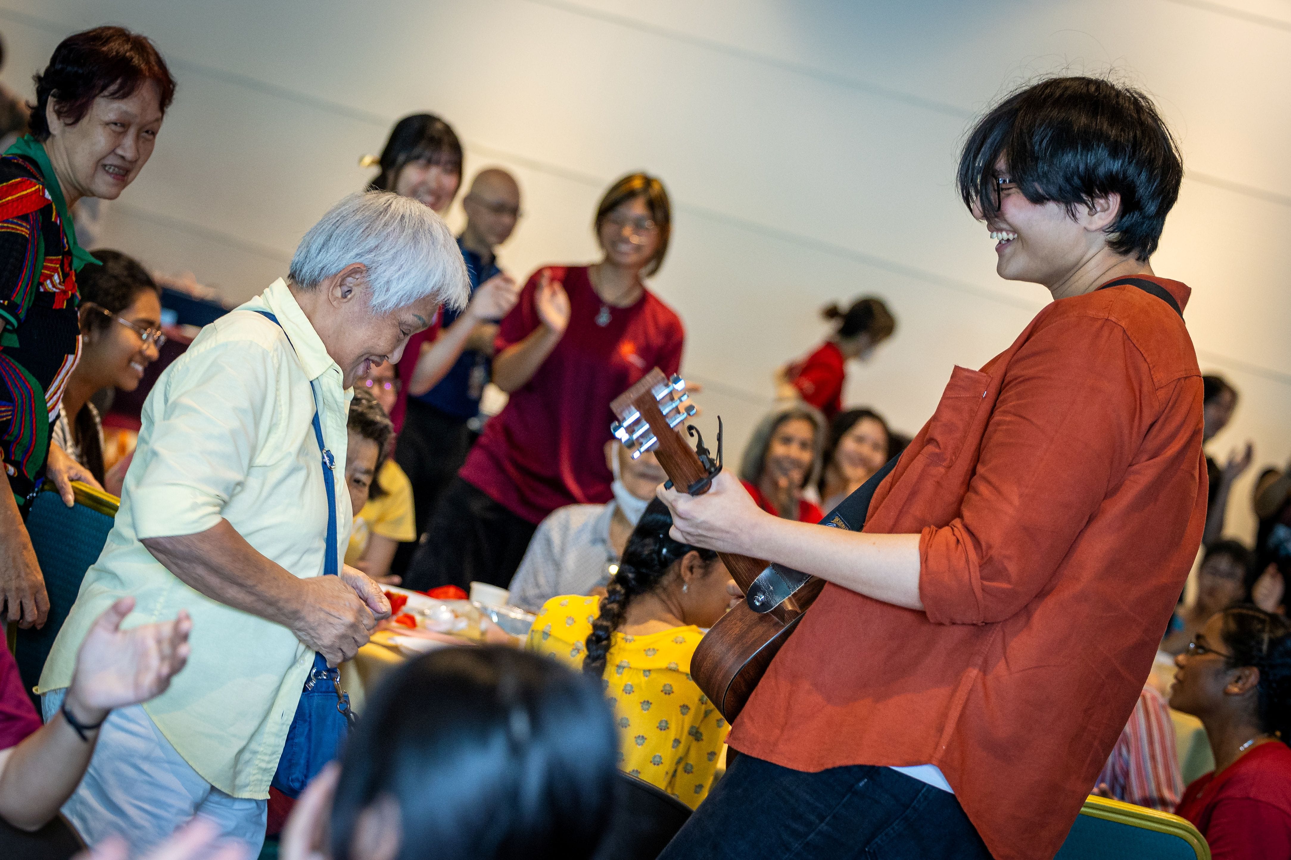 Image of a student guitarist performing with an elderly participant at Magical Autumn