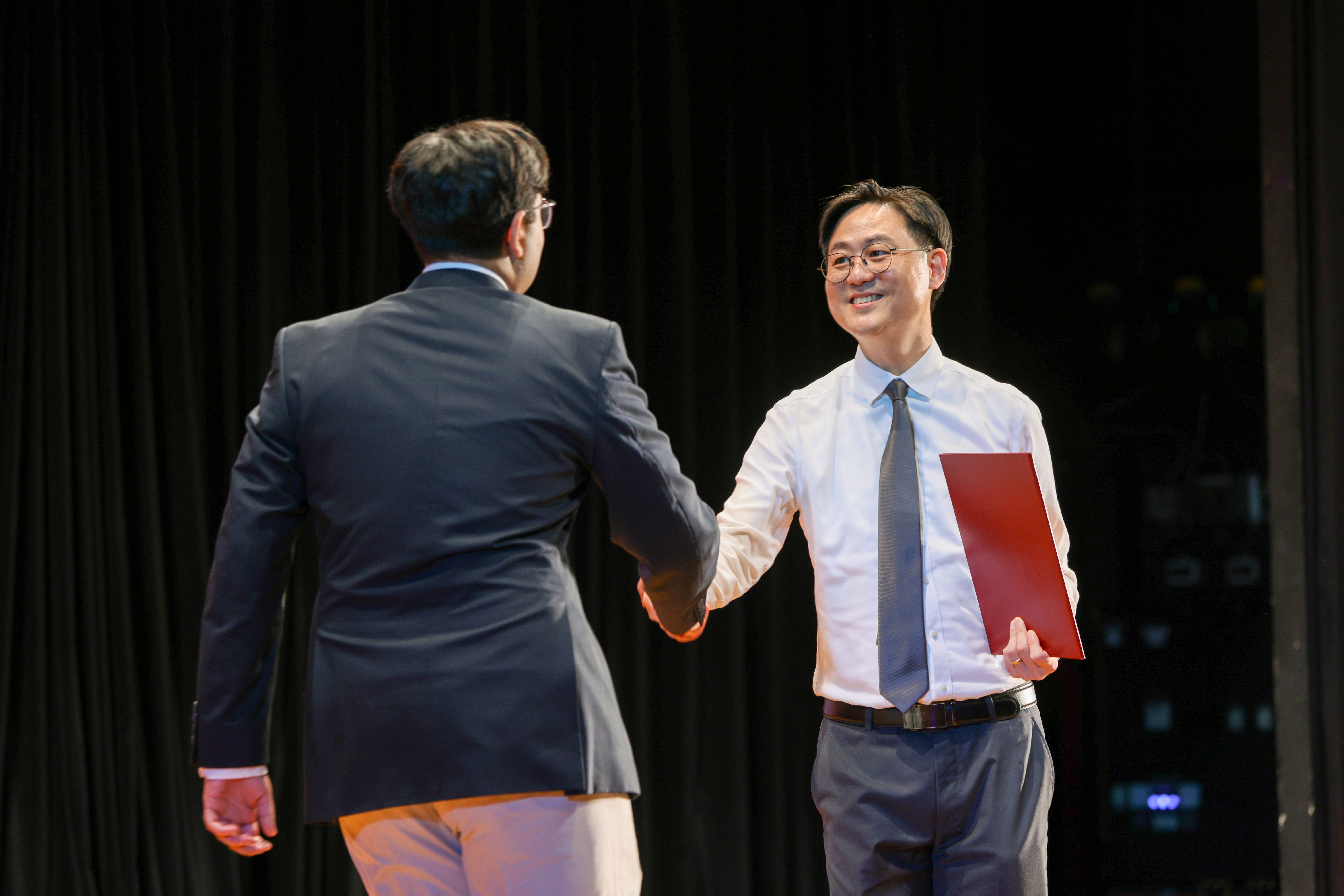 Image of a student shaking hands with Mr Patrice Choong on stage at the TP Scholarships Presentation