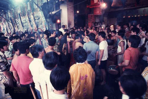 Large crowd of people gathered inside a decorated temple during a cultural or religious ceremony.
