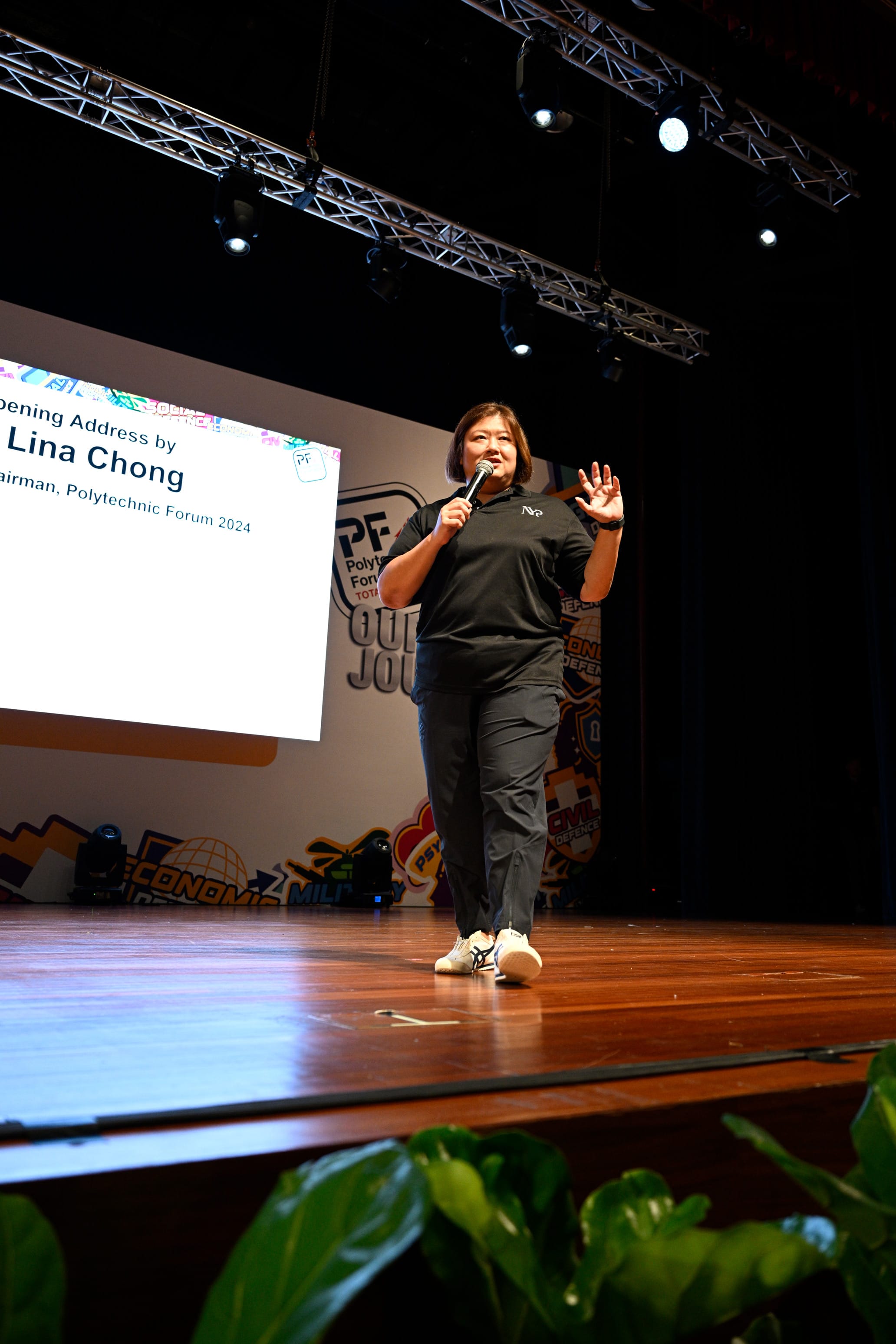 Woman named Lina Chong speaks on stage at Polytechnic Forum 2024, holding a microphone beside a projected slide.