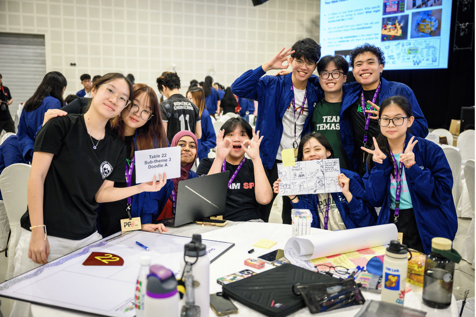 Students posing for the camera while showcasing their work