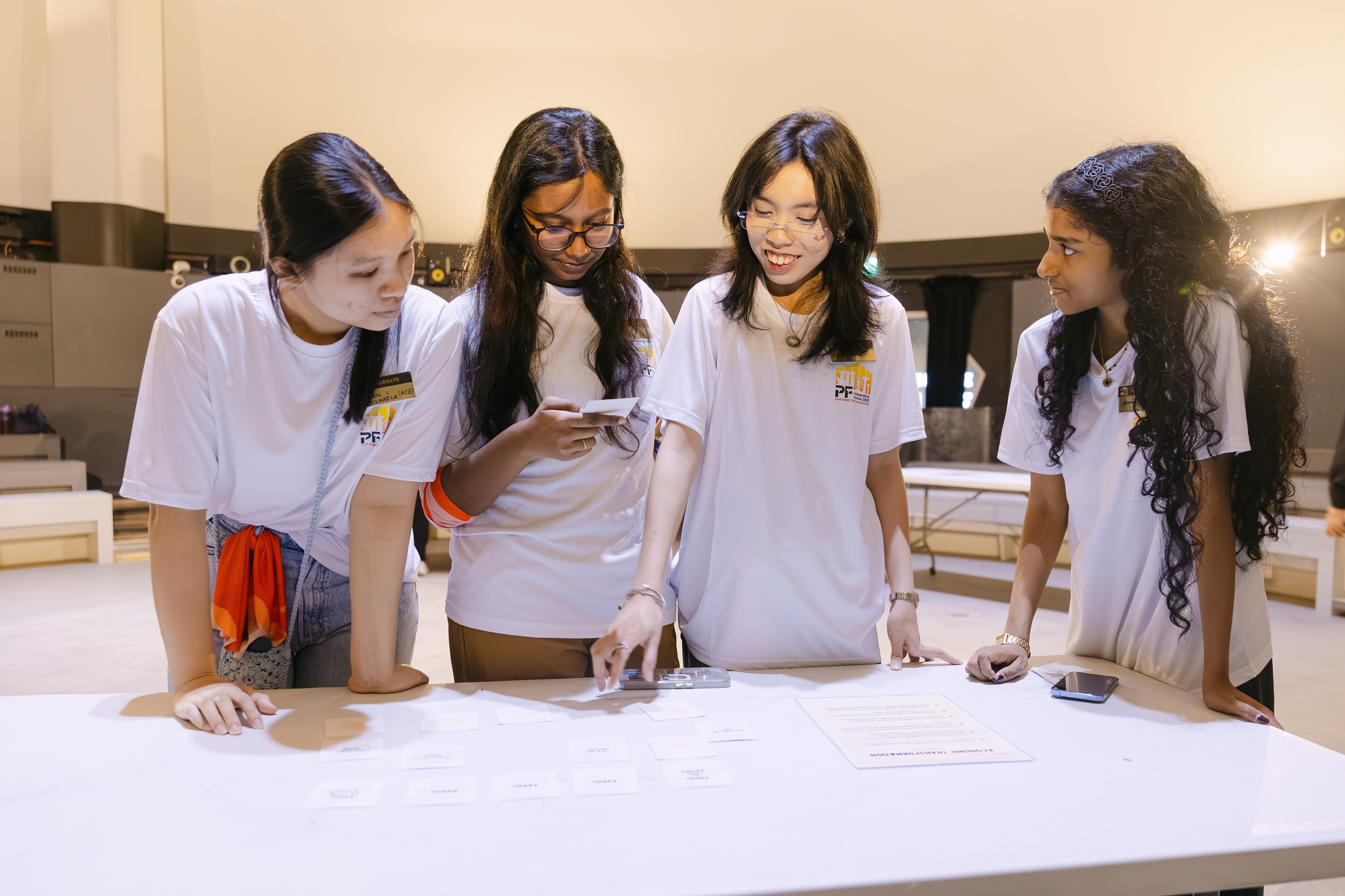 Four ladies in white shirt discussing while looking down at a paper