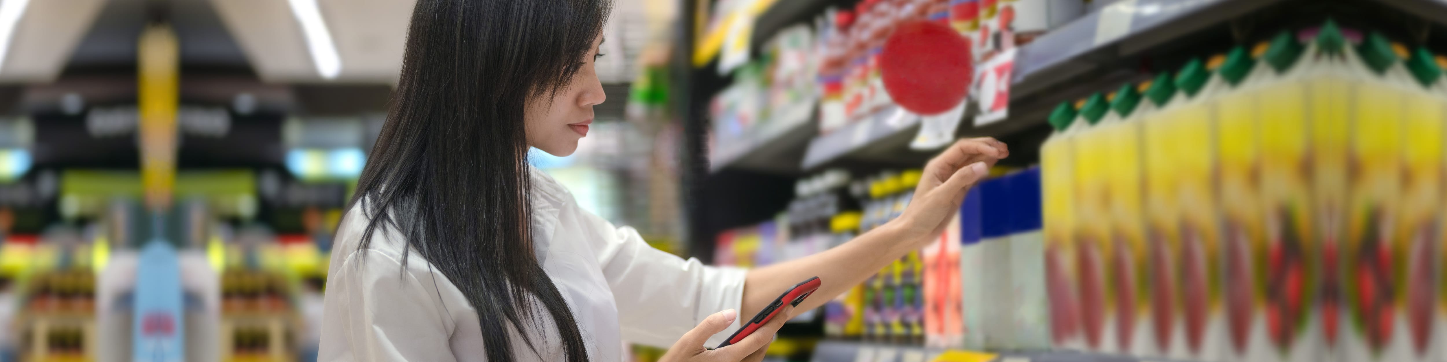 A woman shopping for beverages in a supermarket aisle.