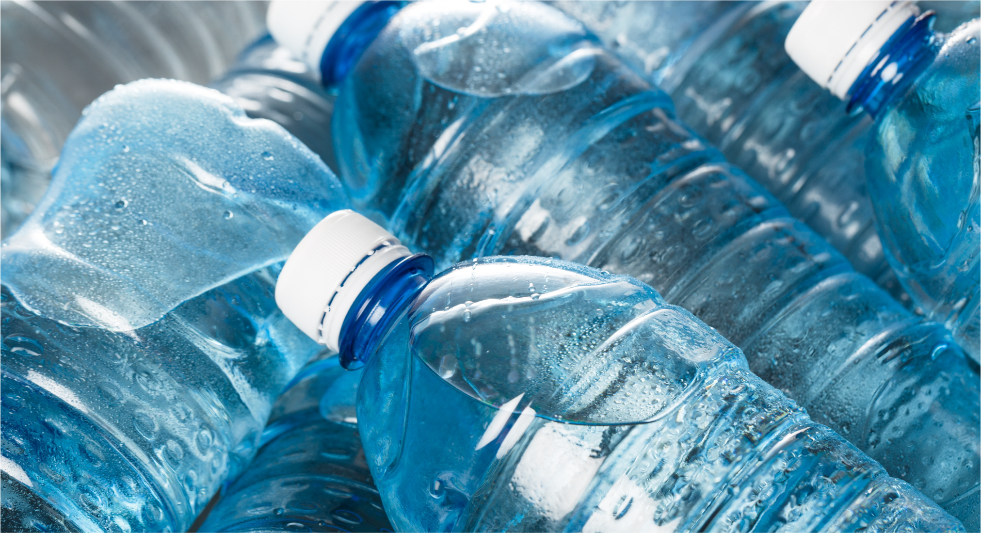 Close-up of multiple plastic bottles filled with drinking water and condensation.