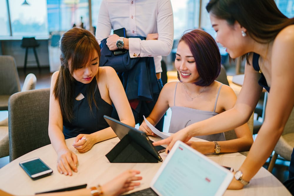 A group of ladies discussing around a table with tablets.
