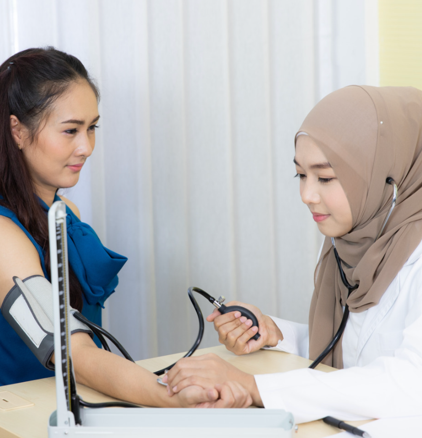 Healthcare worker measuring patient’s blood pressure with sphygmomanometer.