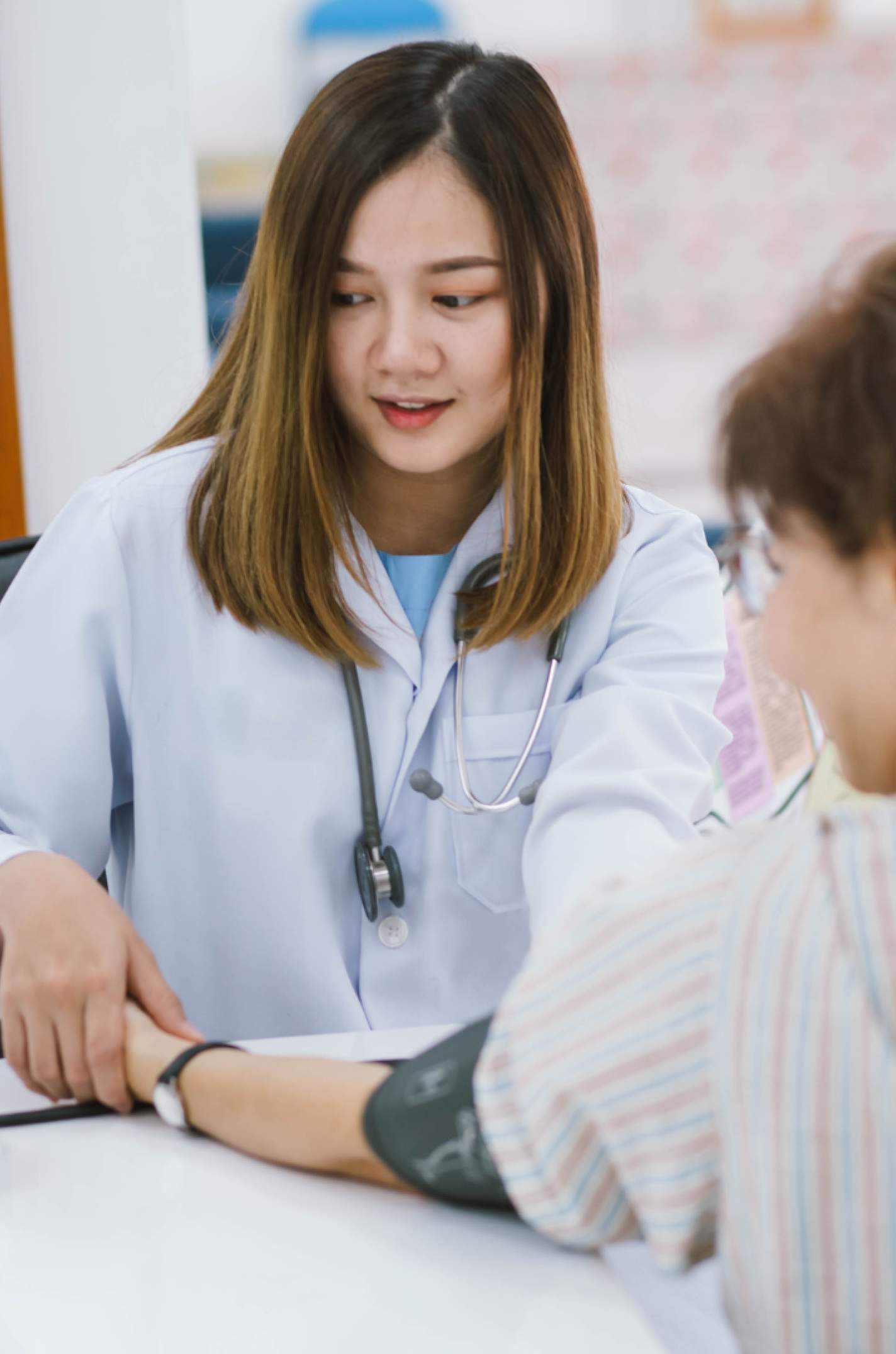 Doctor checking patient's blood pressure with cuff during clinic consultation.