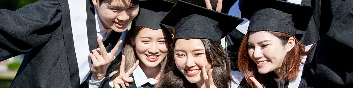 A group of graduates in their graduation gown taking a selfie together.