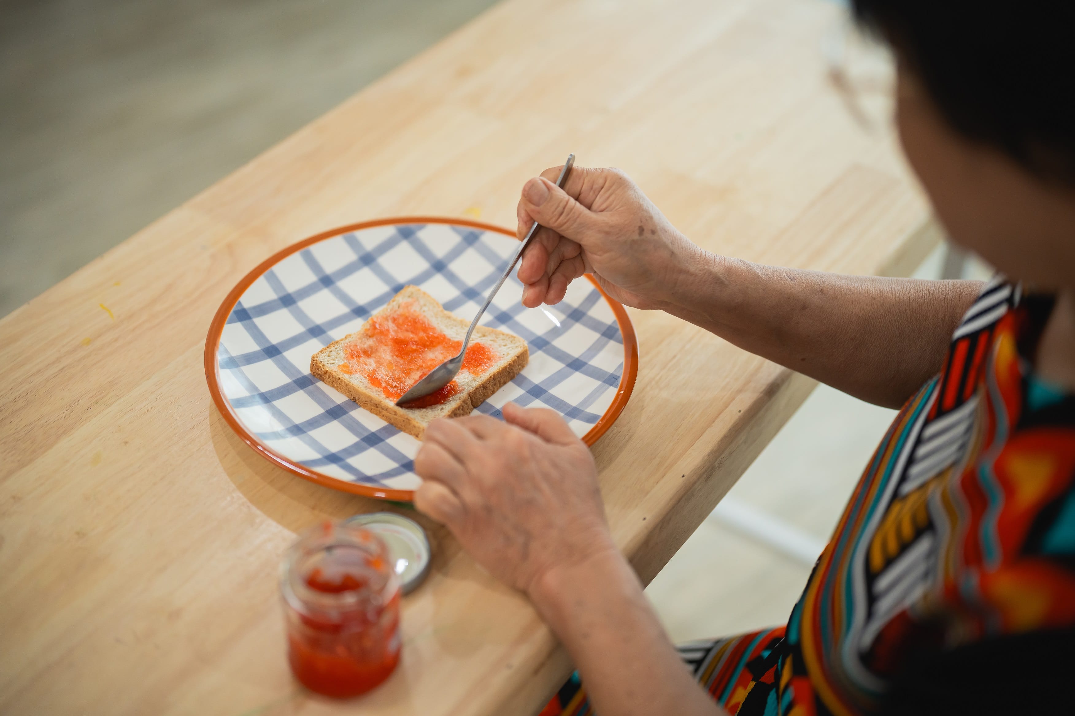 Elderly woman preparing a sandwich on a plate