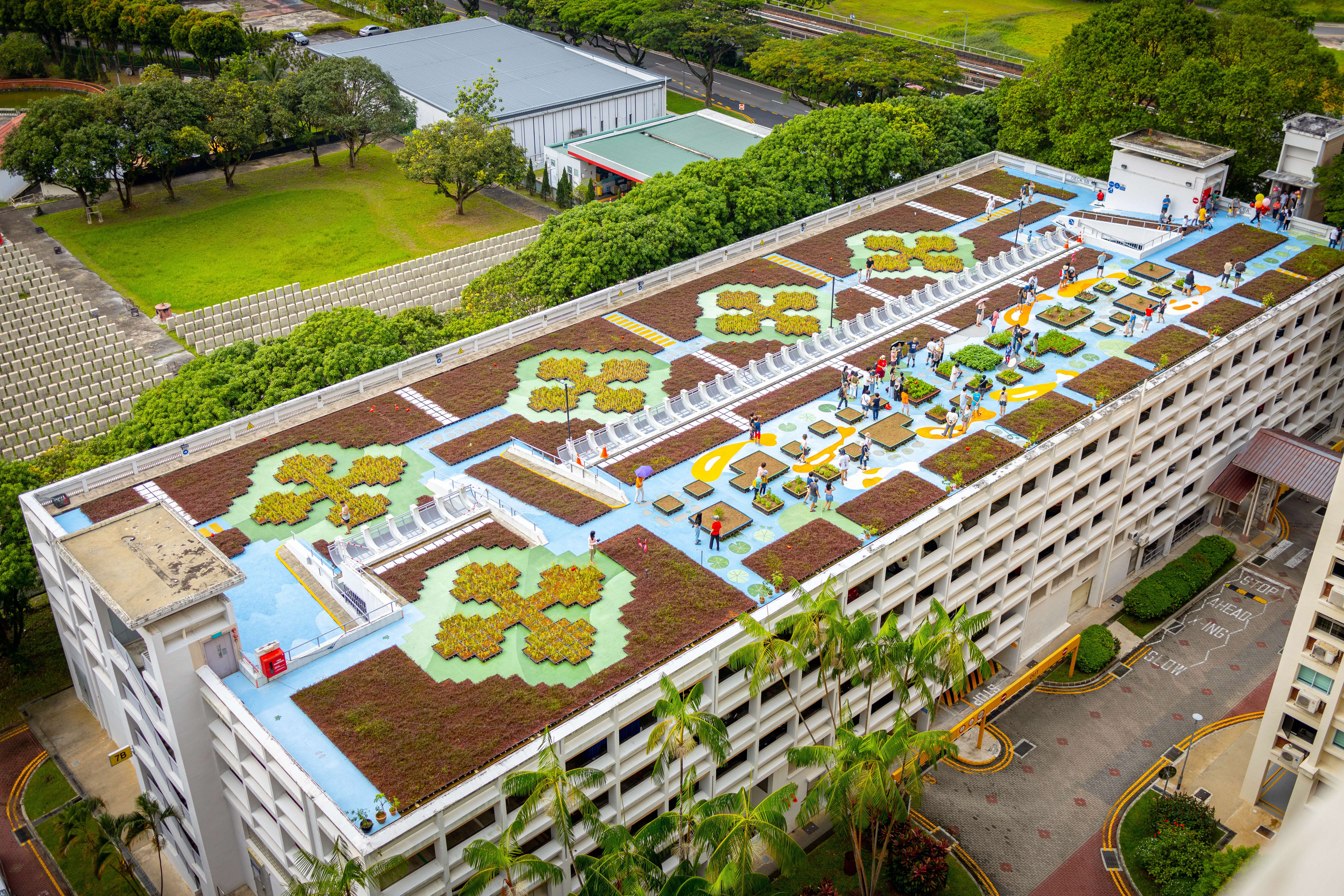Overhead view of multi-story parking garage with rooftop garden and people.