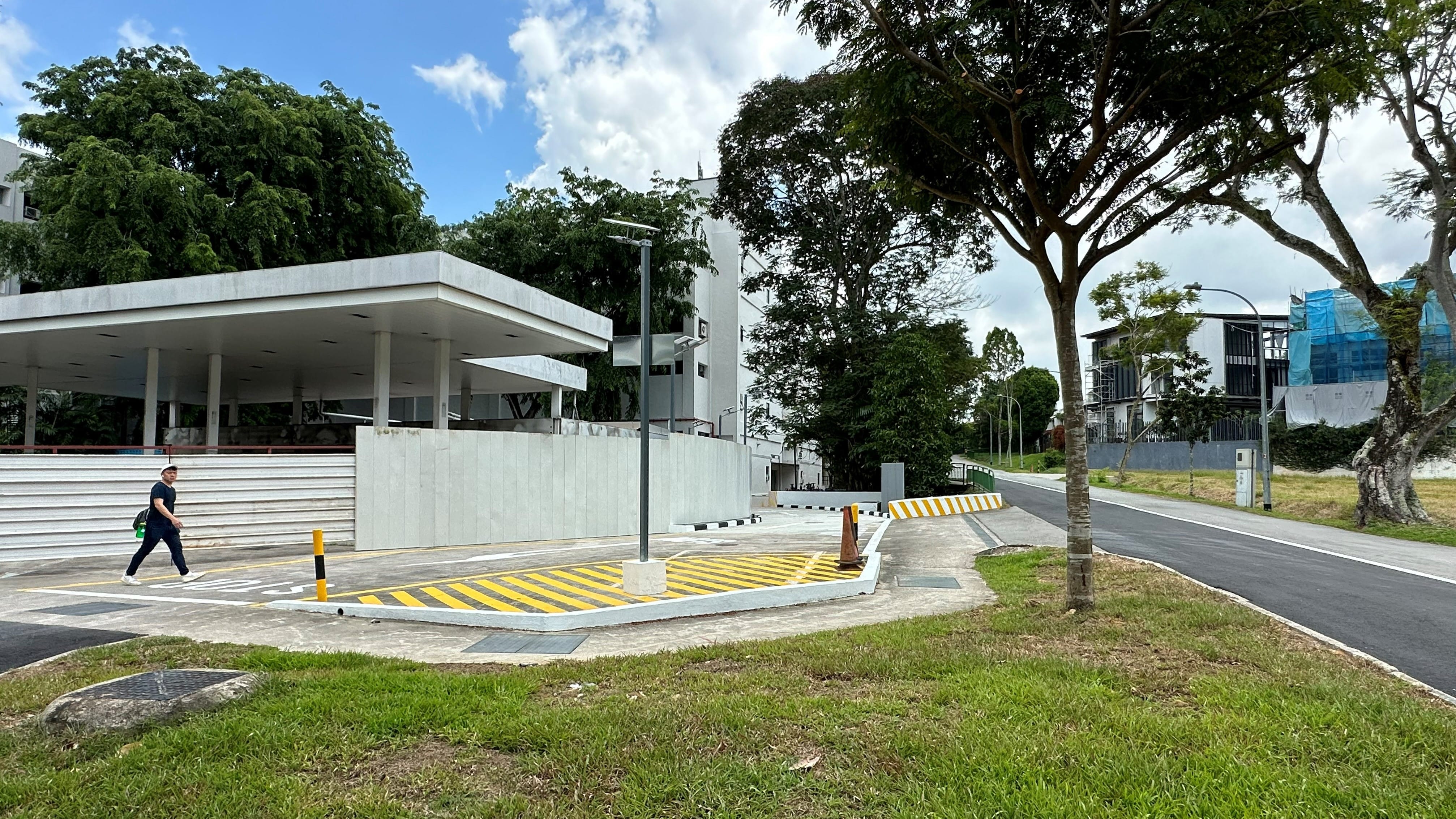Outdoor view of building with covered area, person walking, and road.
