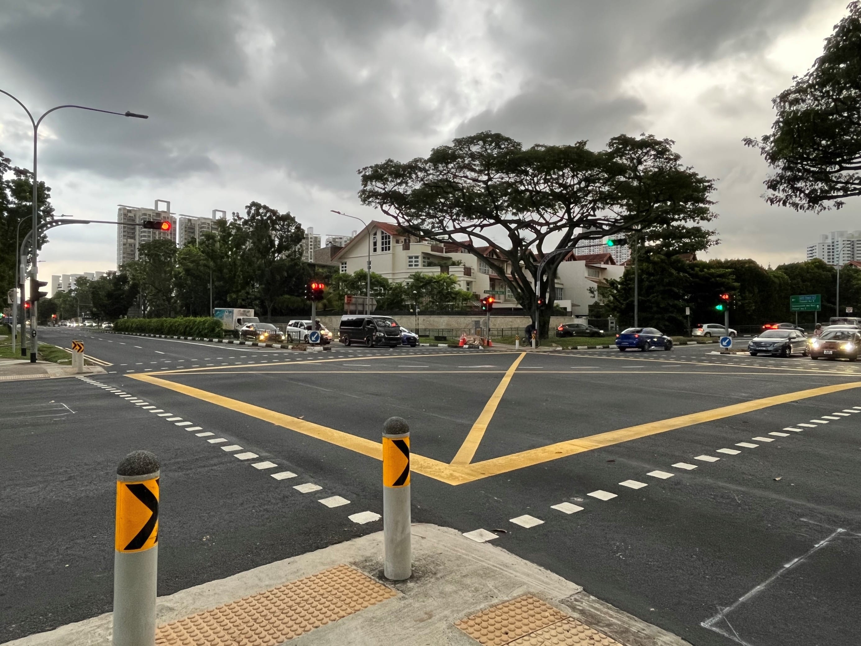 City street view with traffic, yellow crosswalk lines, traffic lights, and cloudy sky.