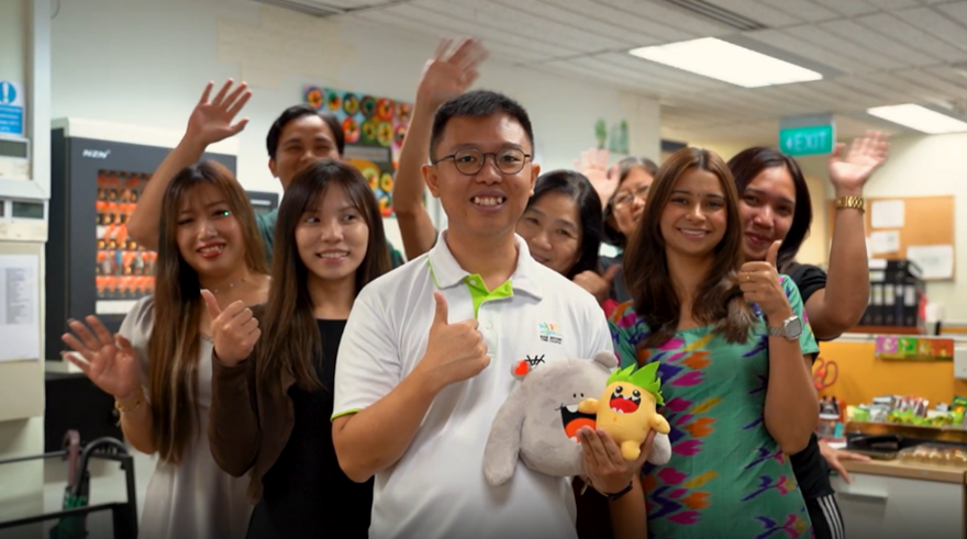 Group of people giving thumbs up and waving, holding branded plush toys.