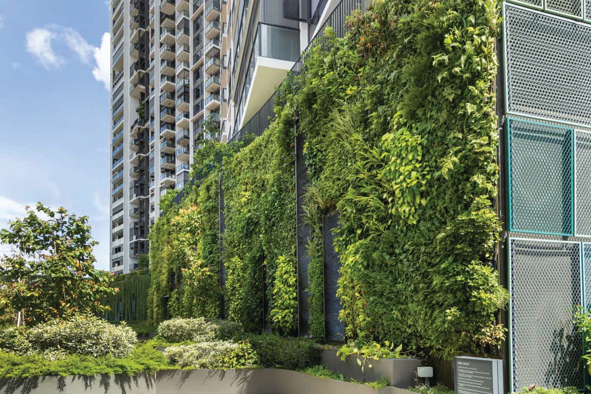 A large vertical green wall covered in lush climbing foliage spans the podium structure of the Gem Residences condominium in Toa Payoh, Singapore, alongside a tall residential high-rise building.