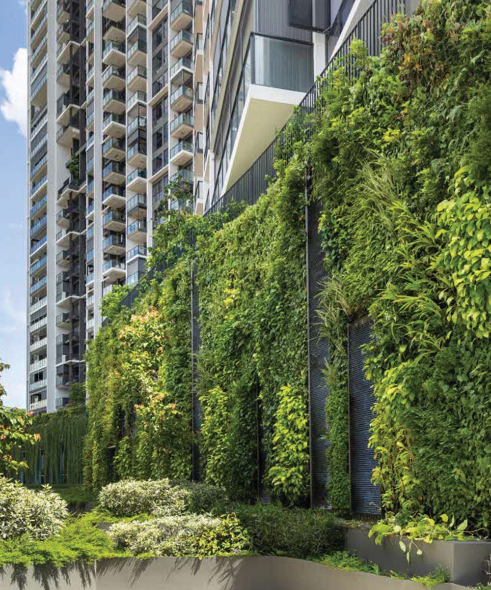 A large vertical green wall covered in lush climbing foliage spans the podium structure of the Gem Residences condominium in Toa Payoh, Singapore, alongside a tall residential high-rise building.