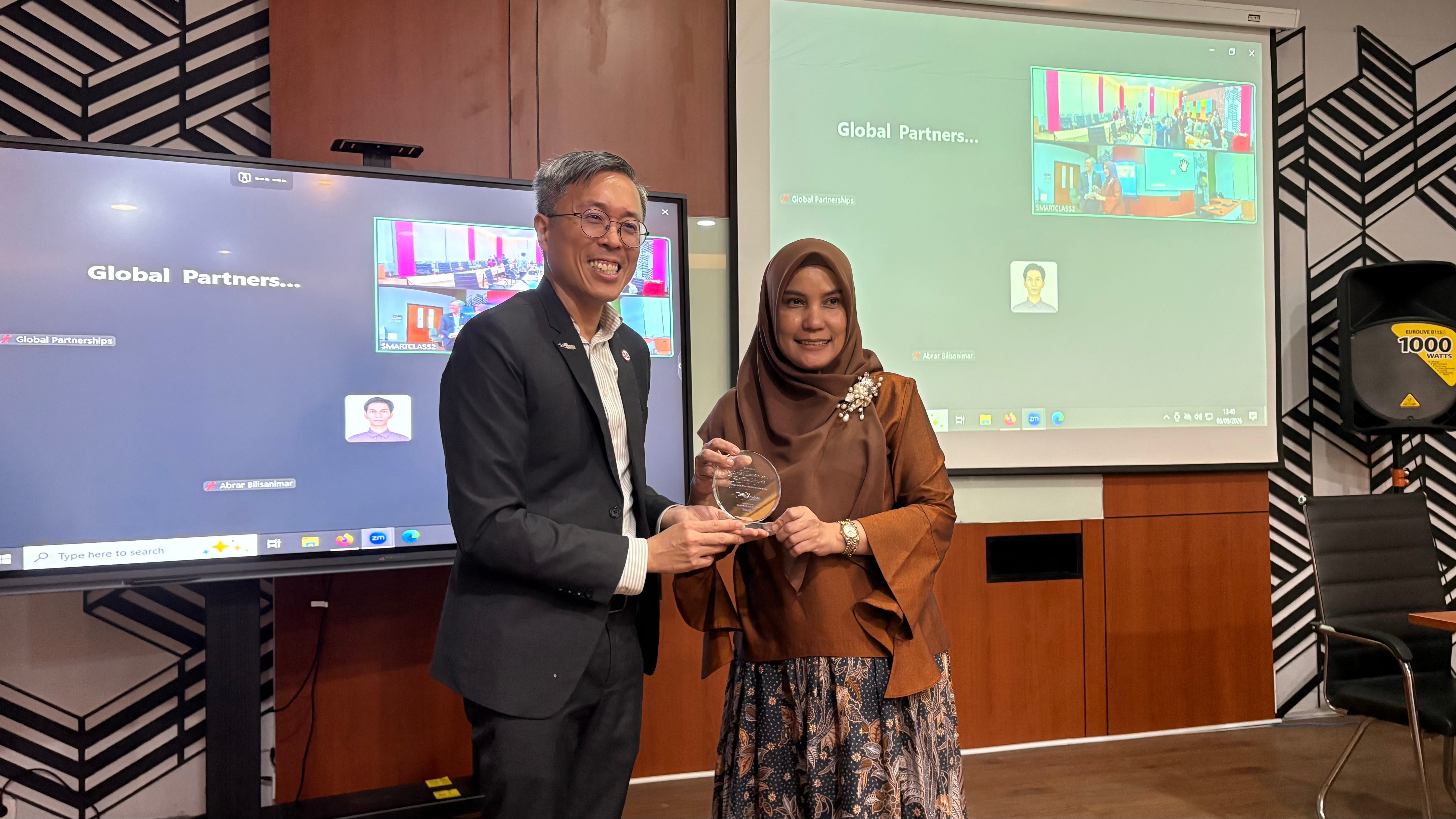 CEO Tax Academy of Singapore, Mr. Dennis Lui, offering a plaque of appreciation to Dean of Prof. Dr. dra. Retno Kusumastuti Hardjono, Dean of FIA UI.