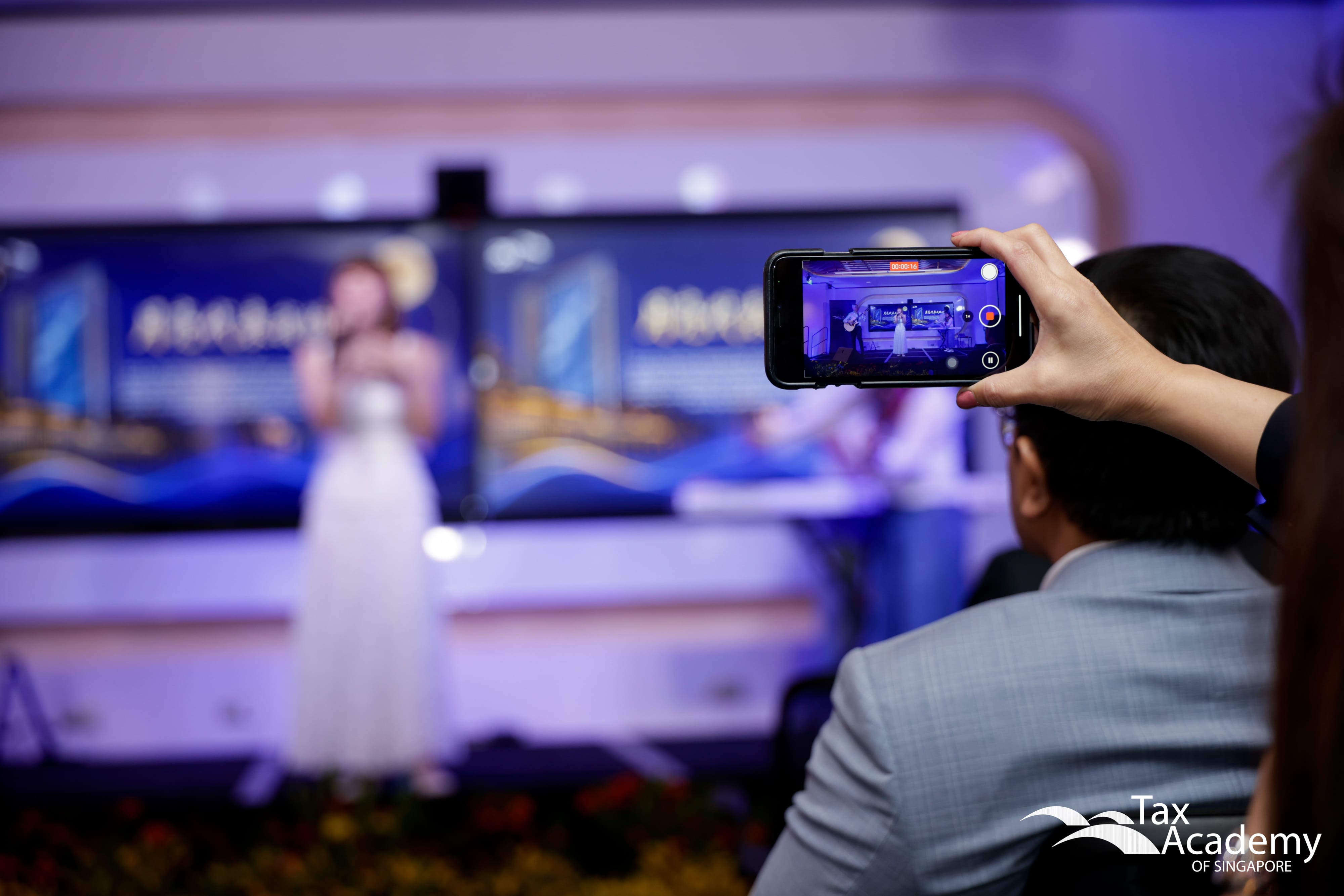 An audience member recording a video of Ms Eunice Toh's singing at the Opening of Tax Academy of Singapore Hub
