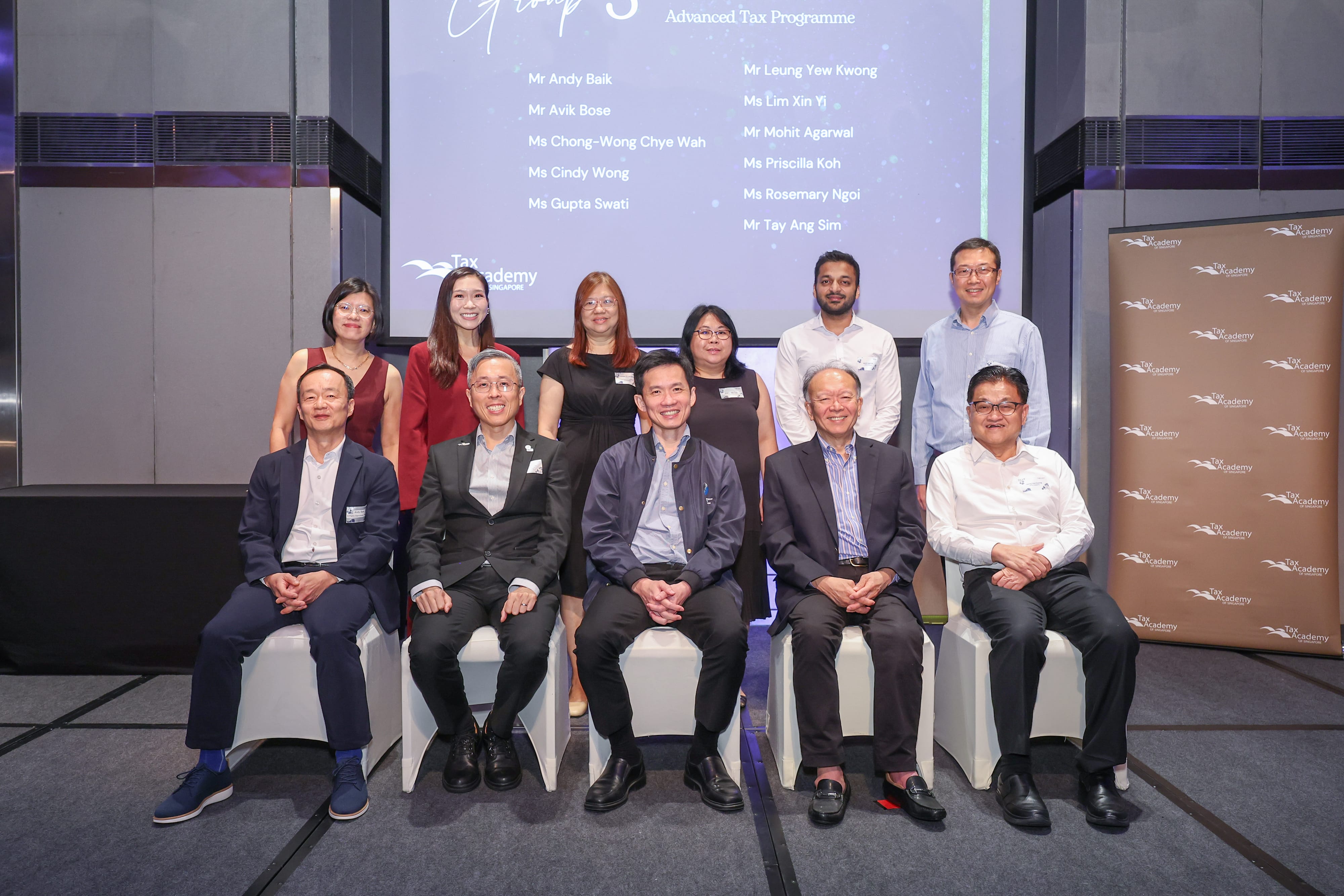 Group photo of 11 people posing in front of a Tax Academy Advanced Tax Programme presentation screen.