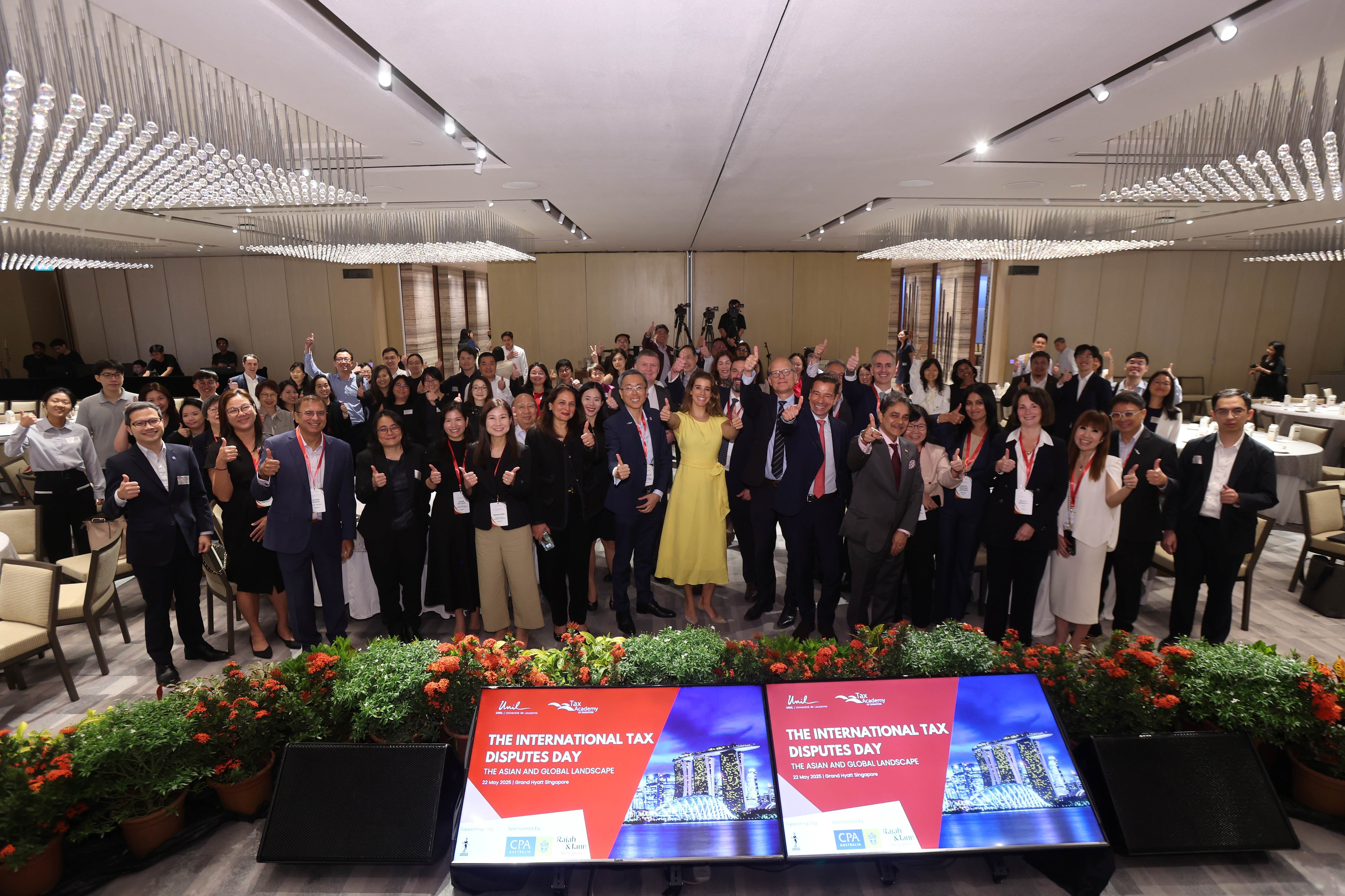 Large group of attendees posing with thumbs up at The International Tax Disputes Day conference in Singapore.