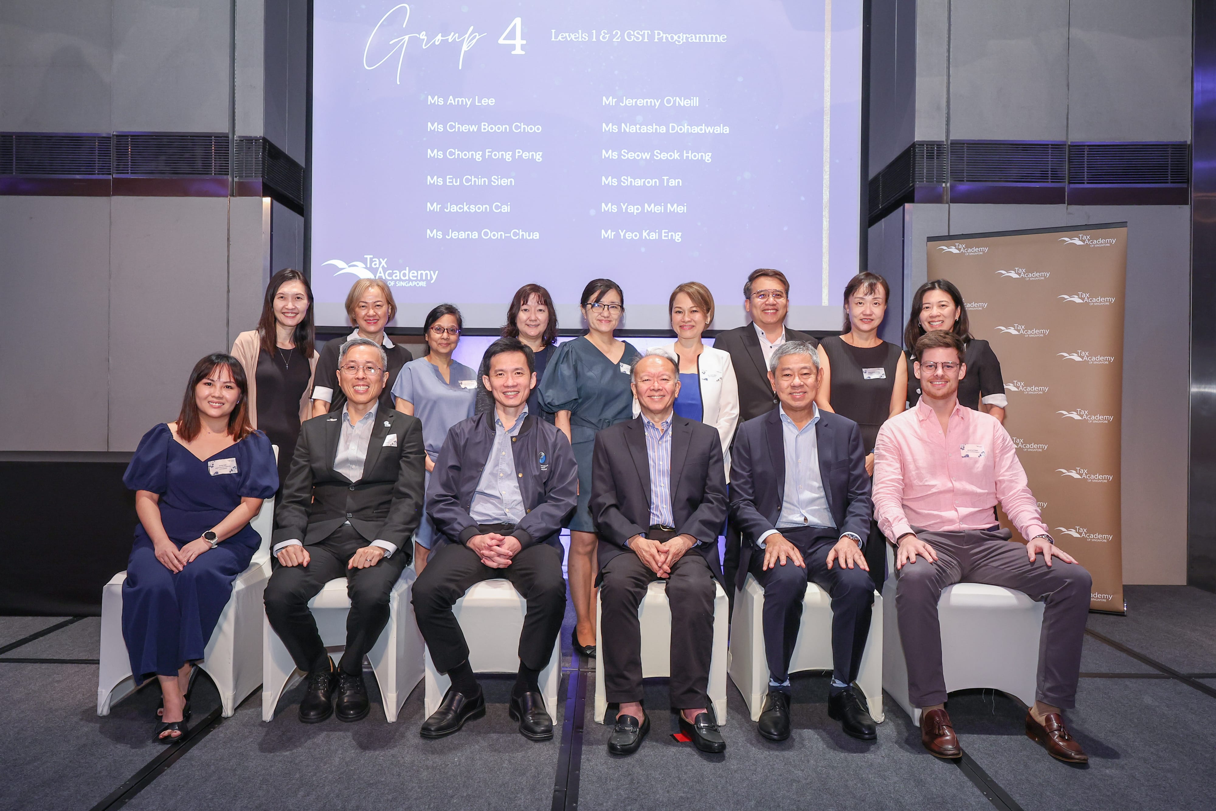 Group photo of about 14 people in front of a Tax Academy Singapore Group 4 GST Programme screen.