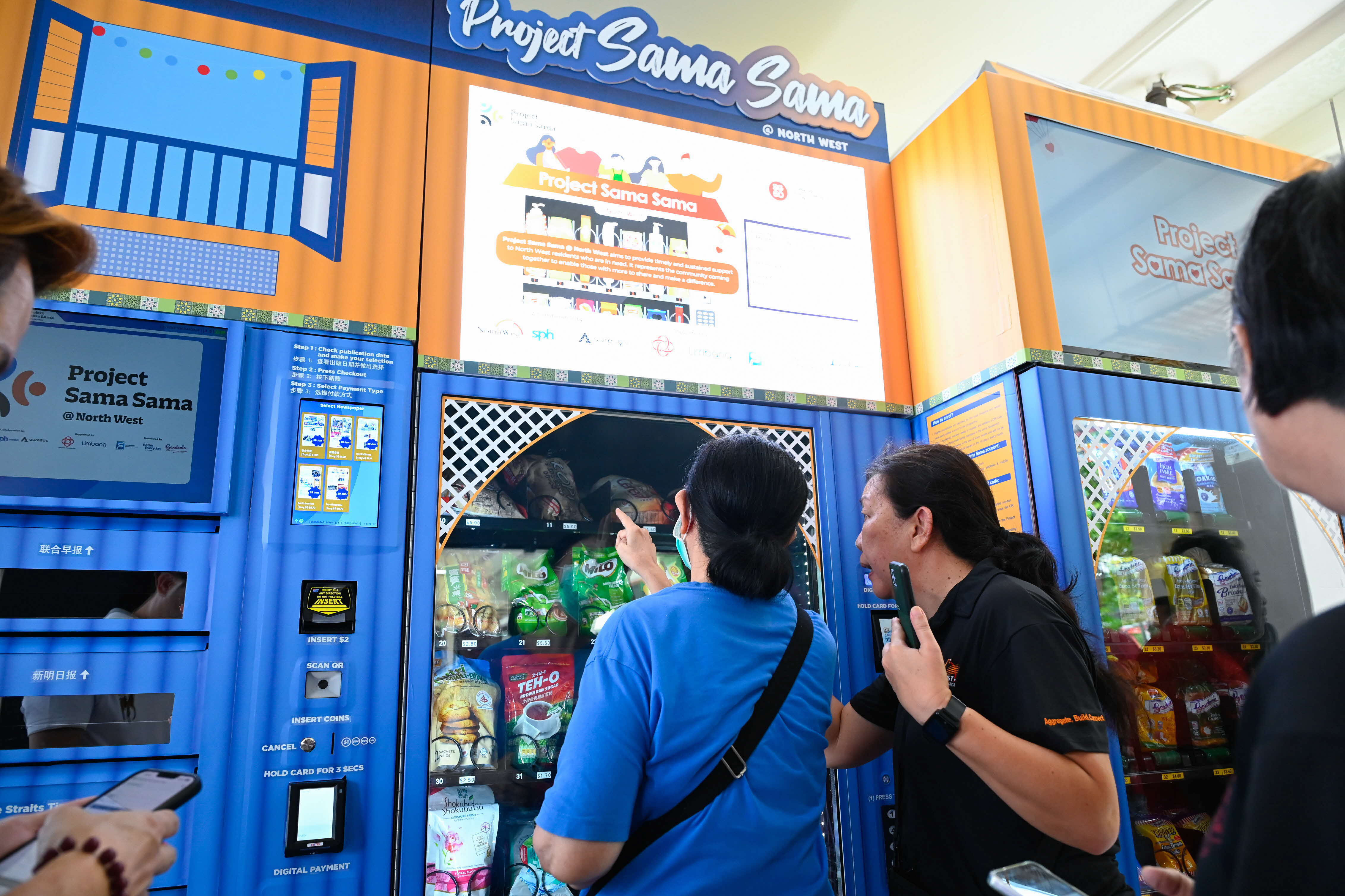A hand pressing a button on a vending machine keypad, with snack-filled shelves visible behind the glass.