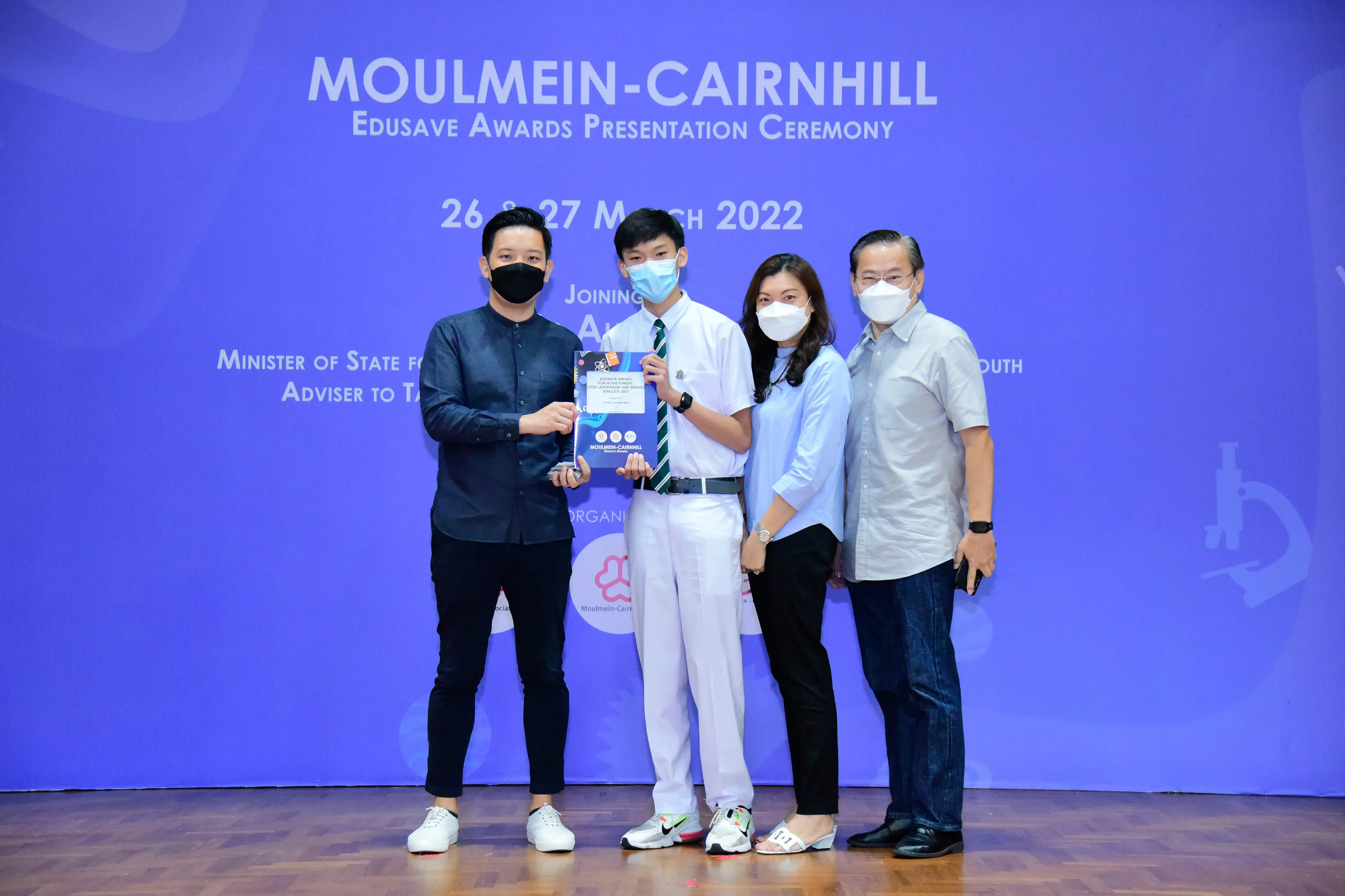Four masked people pose at the Moulmein-Cairnhill Edusave Awards Presentation Ceremony on 26-27 March 2022.