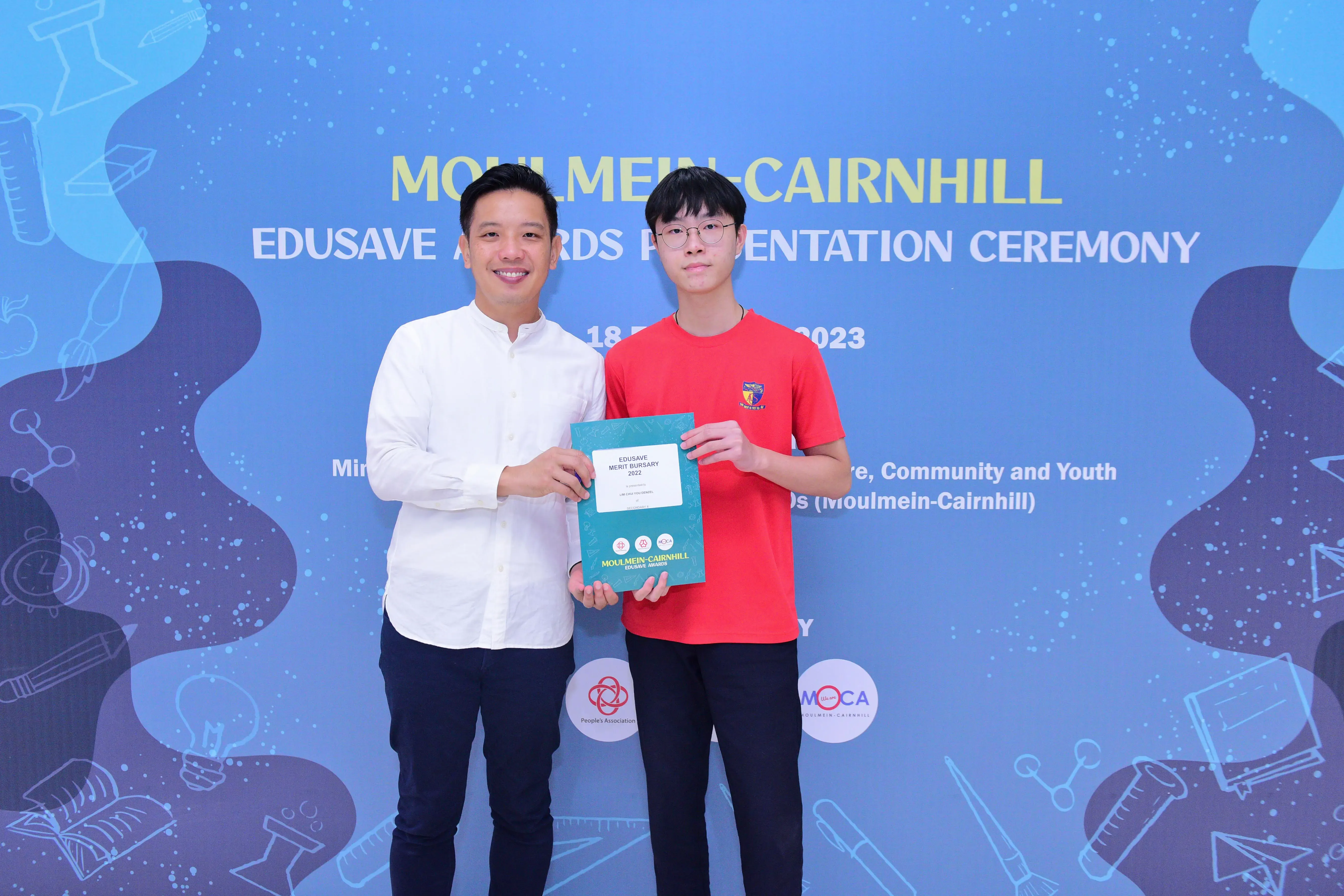 Two men pose holding an Edusave Merit Bursary certificate at the Moulmein-Cairnhill Edusave Awards Ceremony 2023.