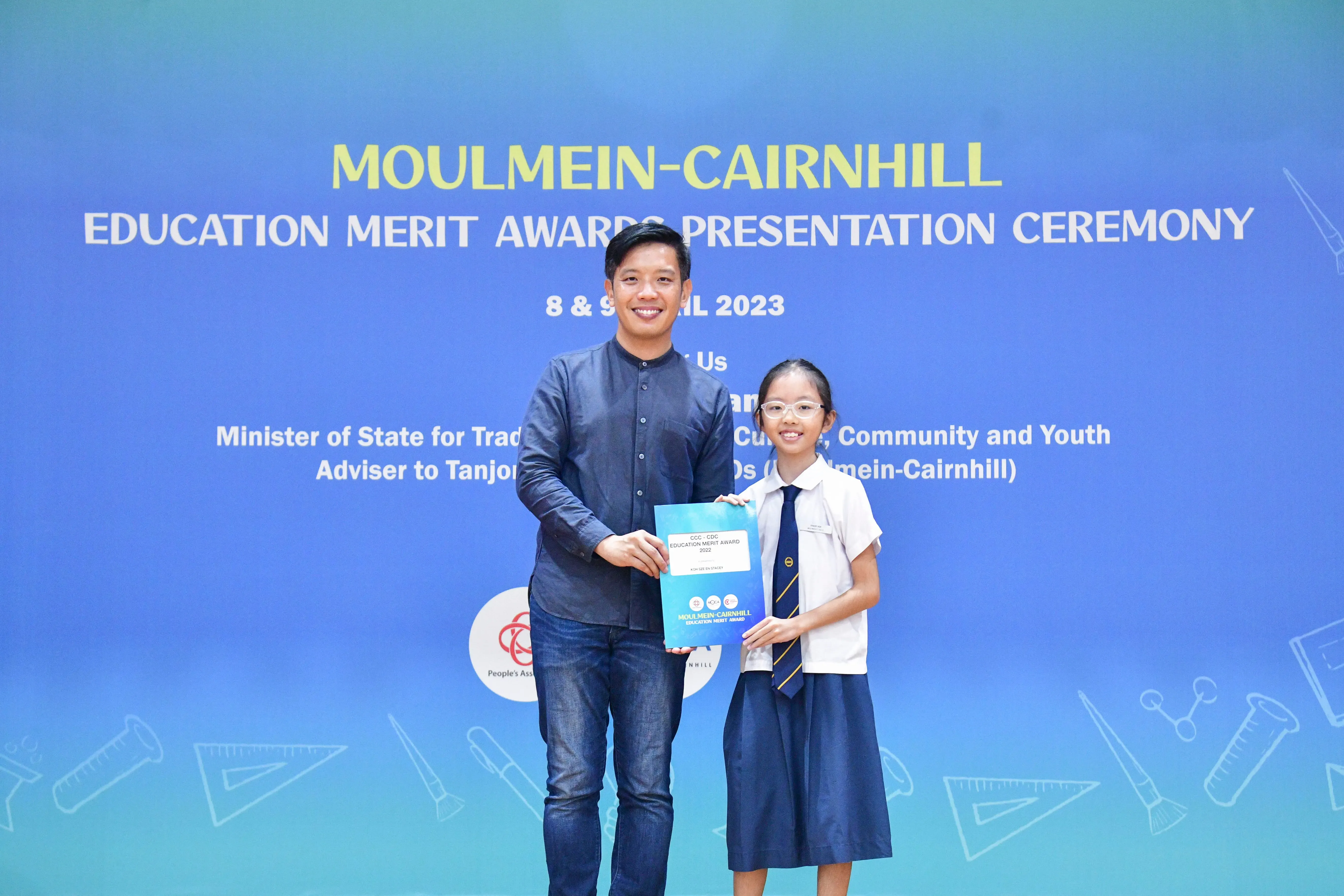 A man and a young girl in school uniform hold an award certificate at the Moulmein-Cairnhill Education Merit Awards 2023.