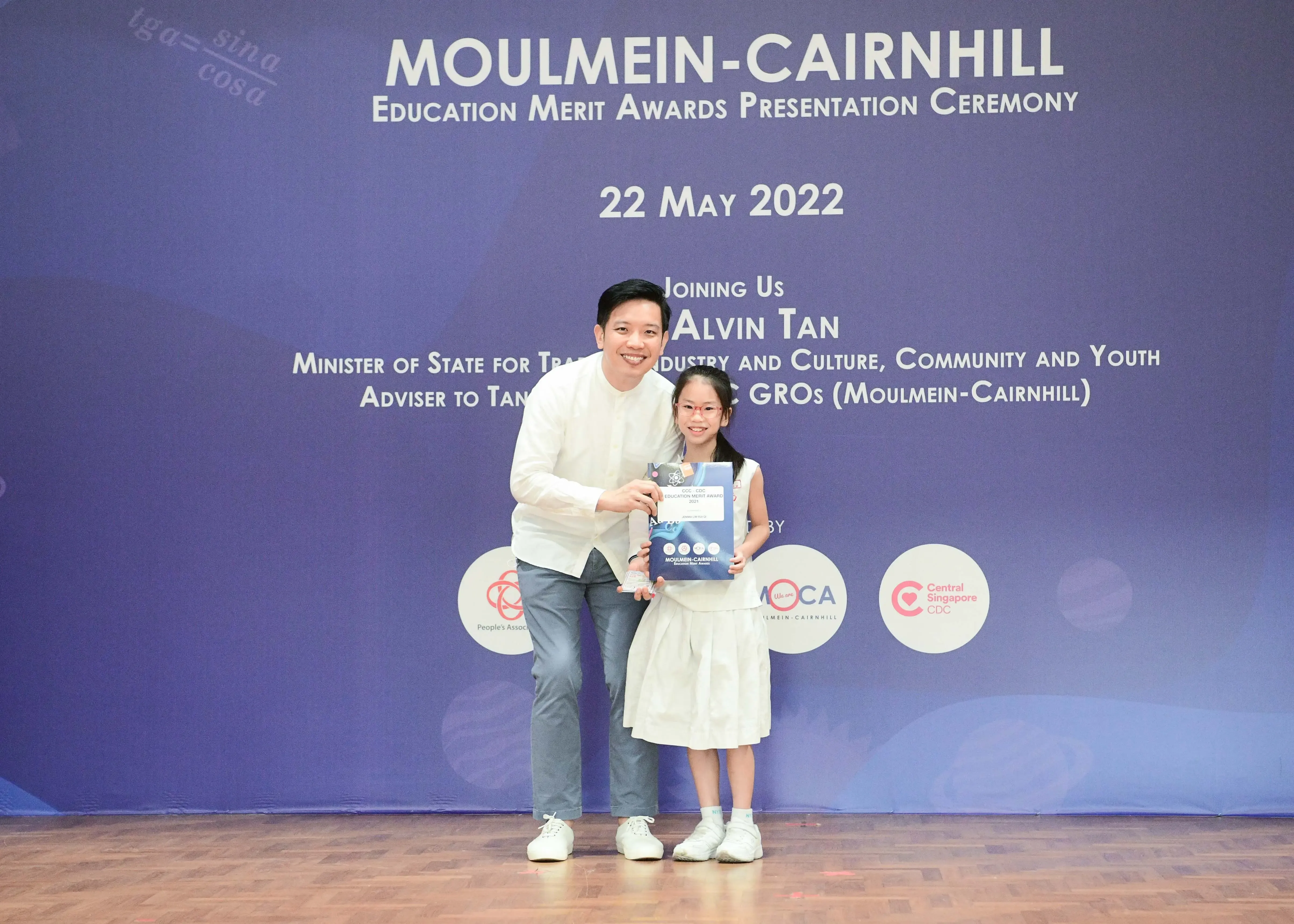 A man and a young girl pose together holding an award at the Moulmein-Cairnhill Education Merit Awards Ceremony, May 2022.