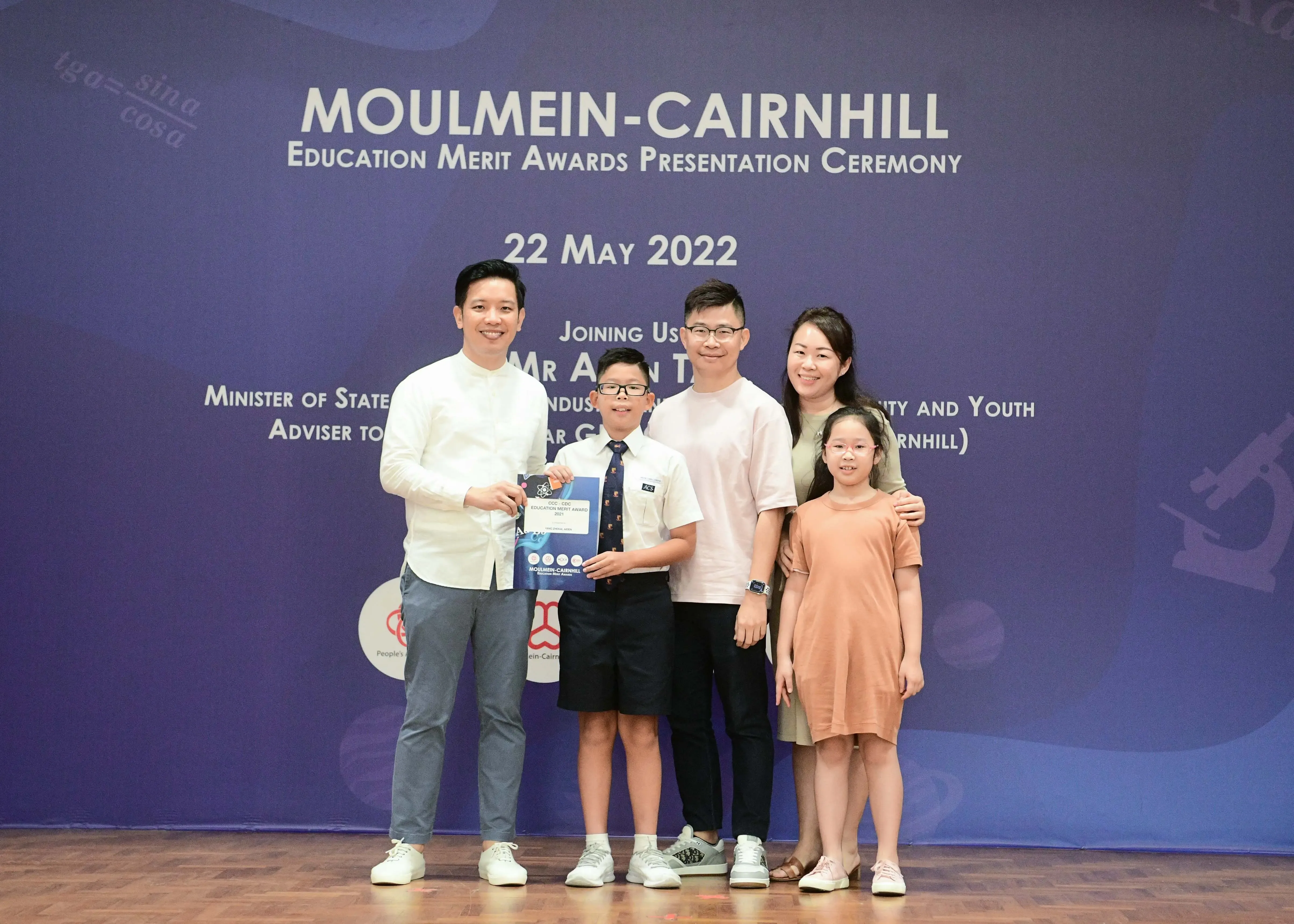 Five people pose on stage at the Moulmein-Cairnhill Education Merit Awards Presentation Ceremony on 22 May 2022.