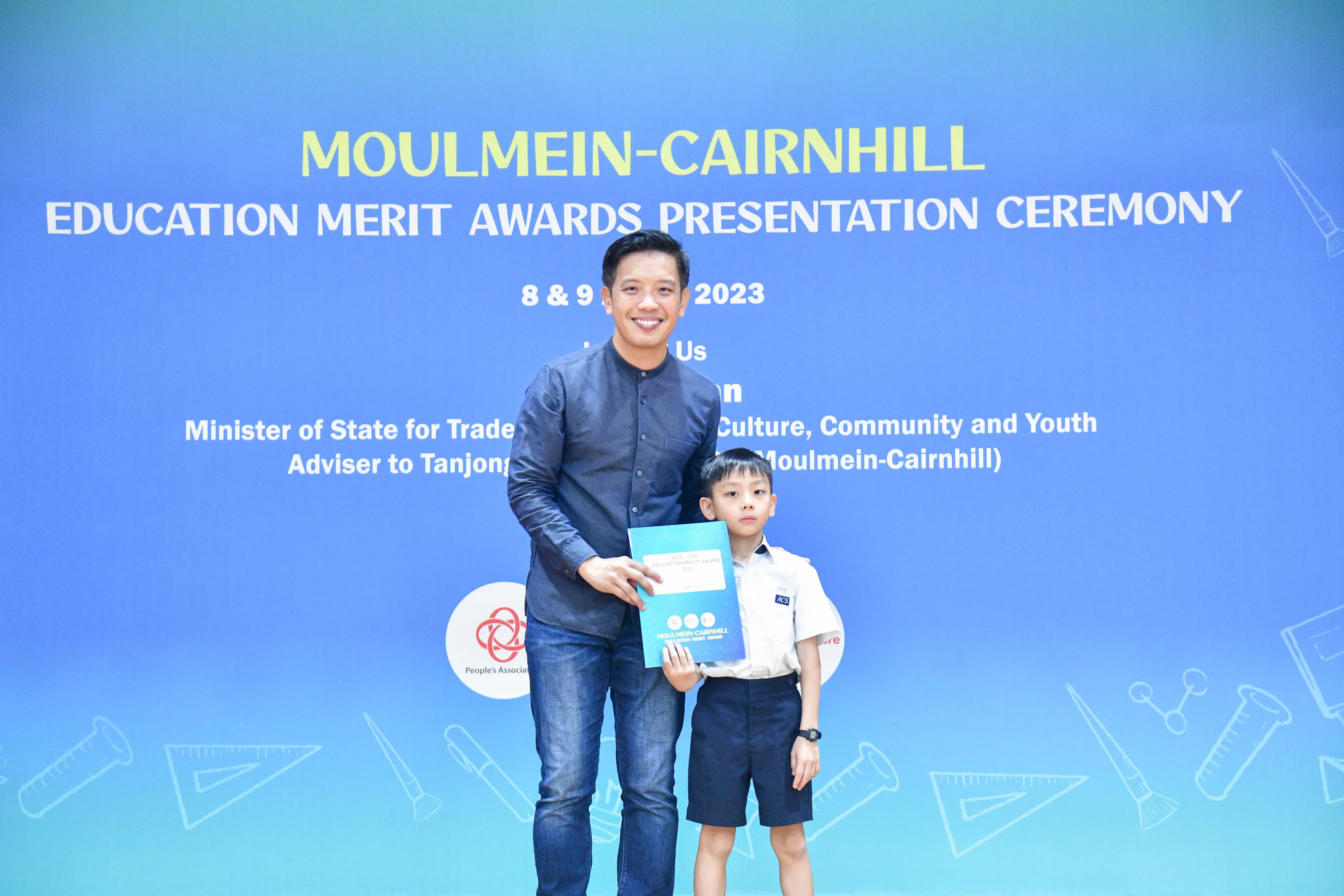 A man and a young boy pose together holding an award at the Moulmein-Cairnhill Education Merit Awards Ceremony 2023.