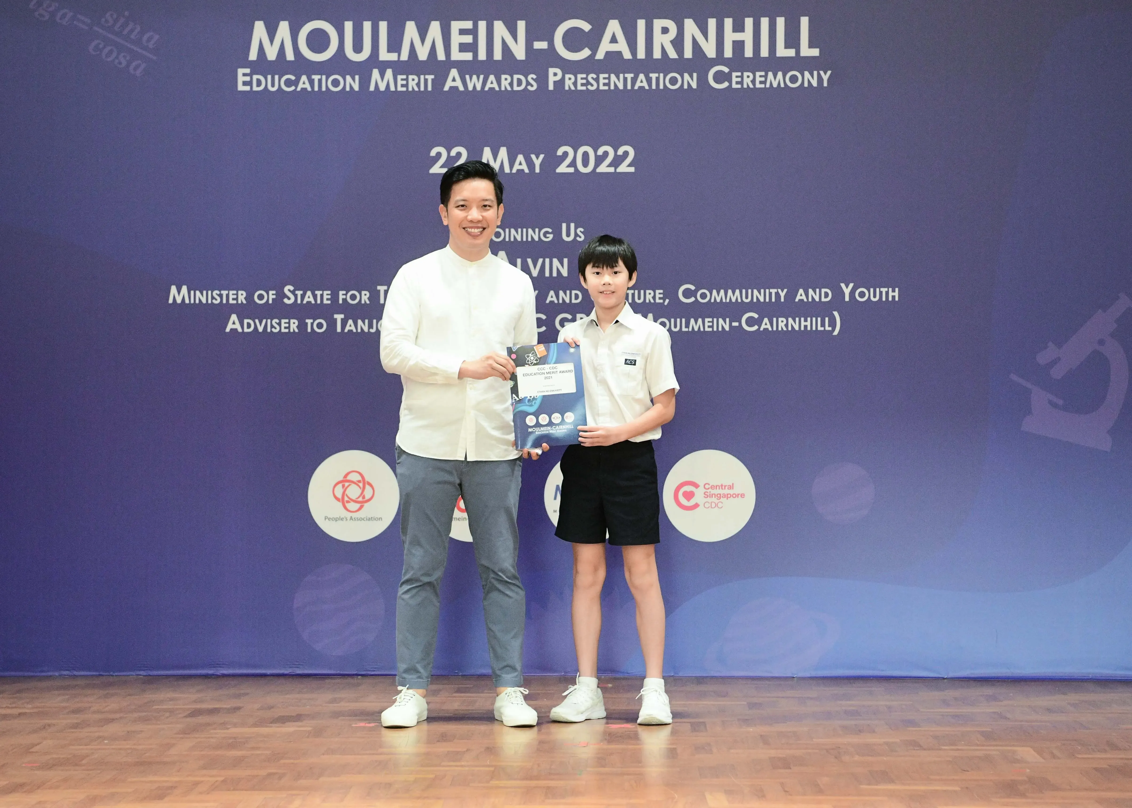 An adult and a young student hold an award certificate at the Moulmein-Cairnhill Education Merit Awards on 22 May 2022.