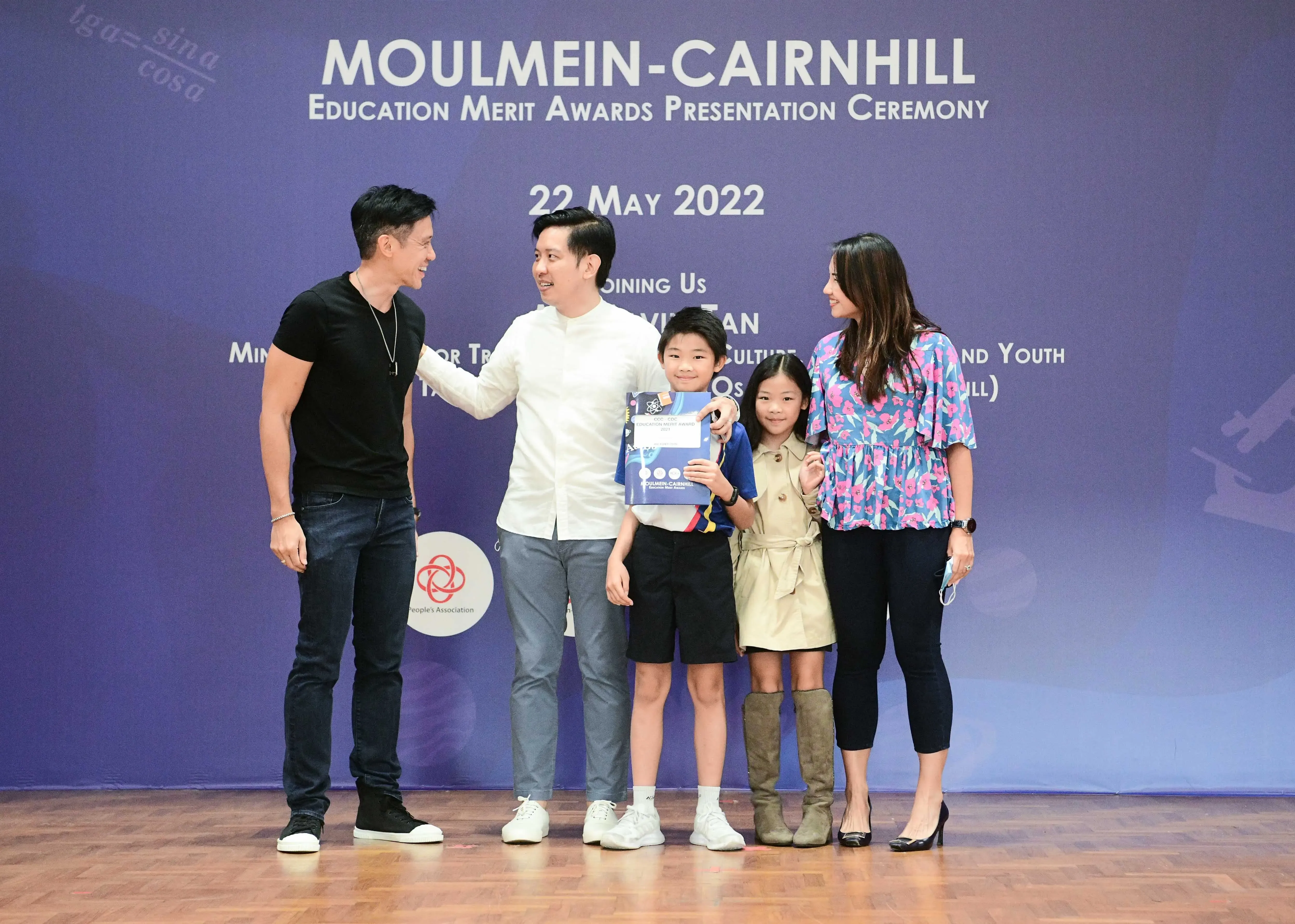 Five people pose on stage at the Moulmein-Cairnhill Education Merit Awards Presentation Ceremony on 22 May 2022.