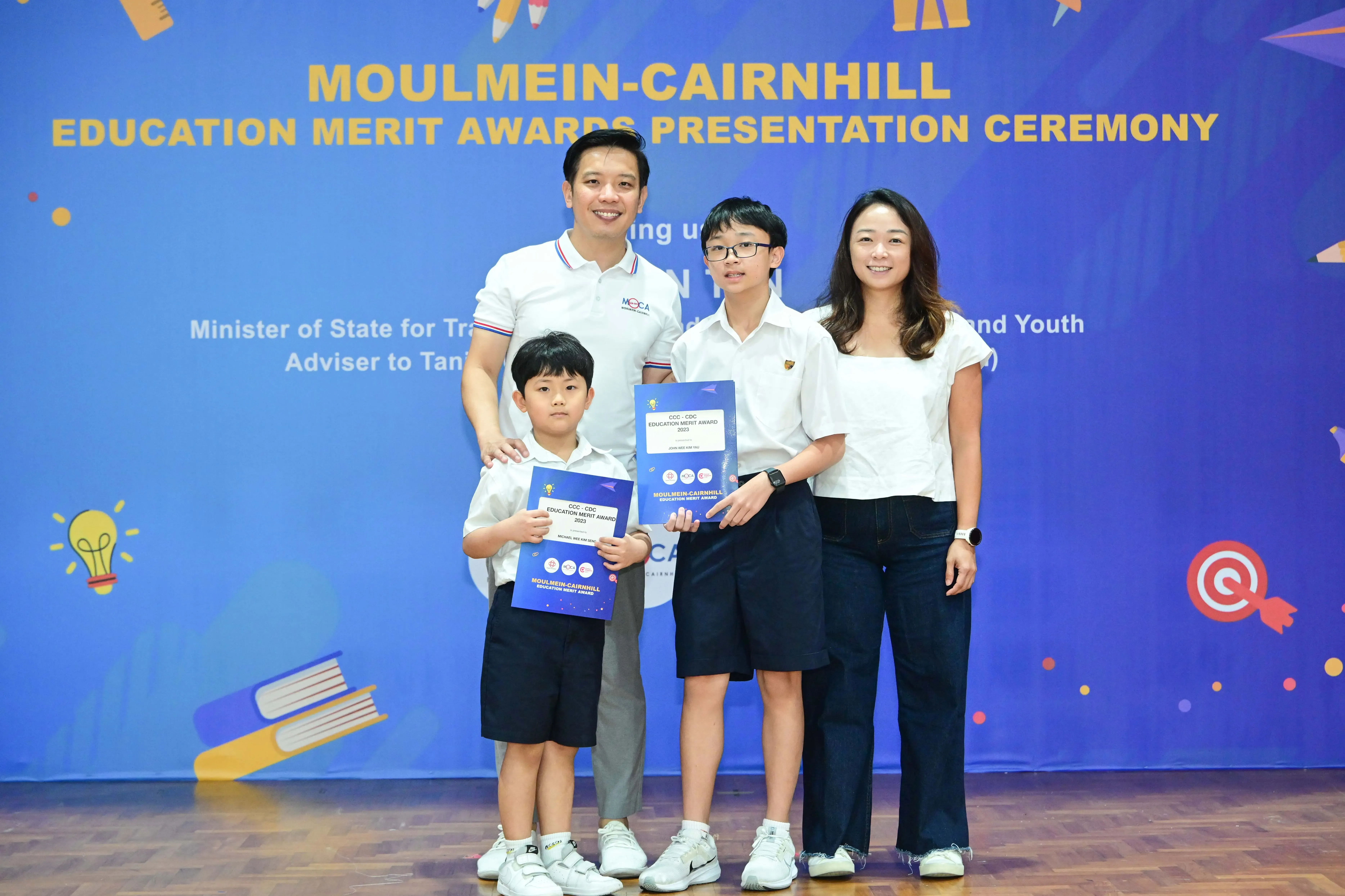 Family of four posing with award certificates at the Moulmein-Cairnhill Education Merit Awards Presentation Ceremony.
